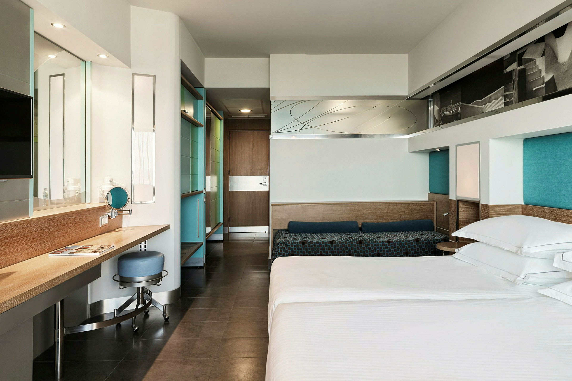 Et moderne hotellrom med en seng, skrivebord og stol samt speil og garderobe. (AI-generert tekst)