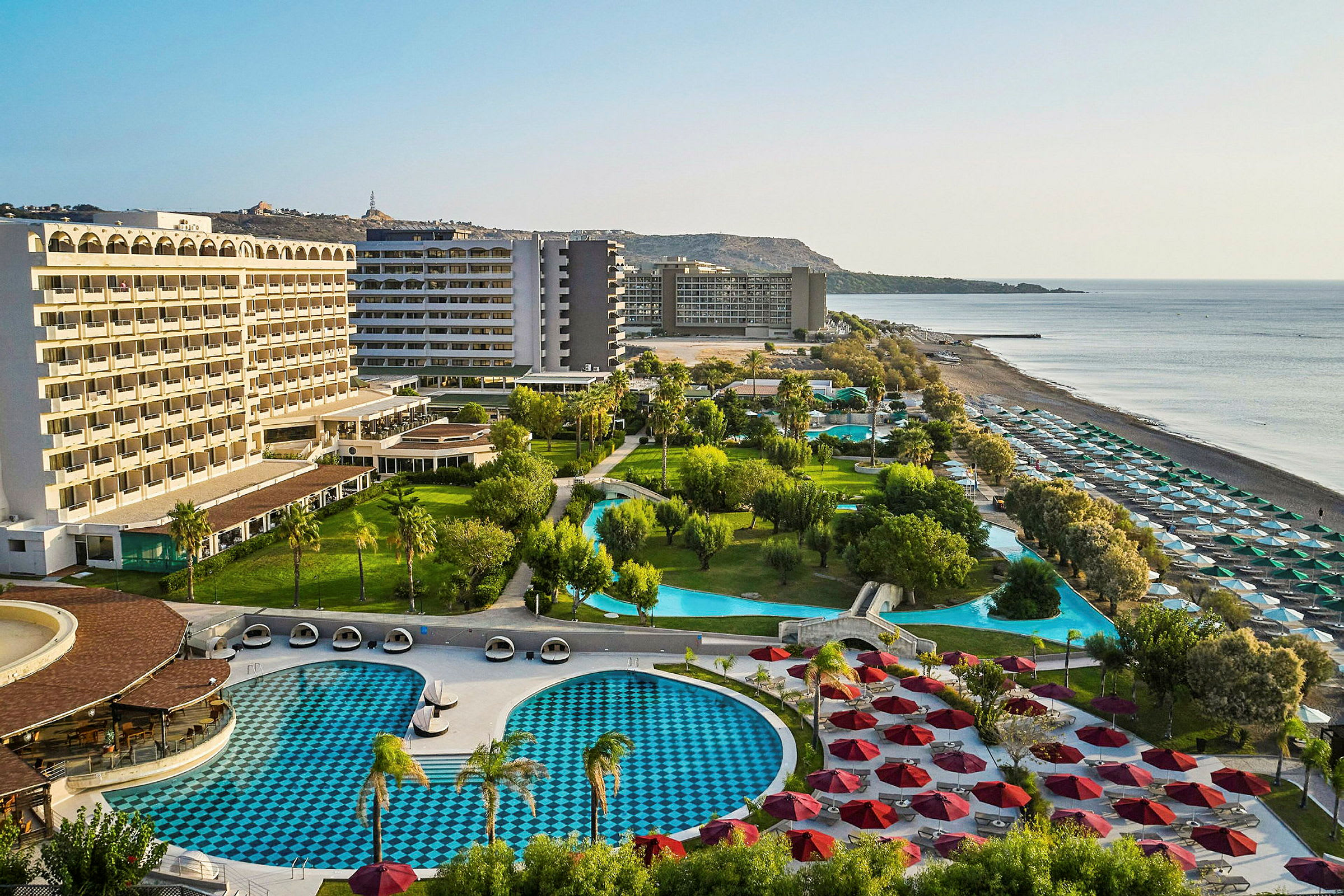 Hotellanlegg med bassenger, grøntområder og strand. (AI-generert tekst)