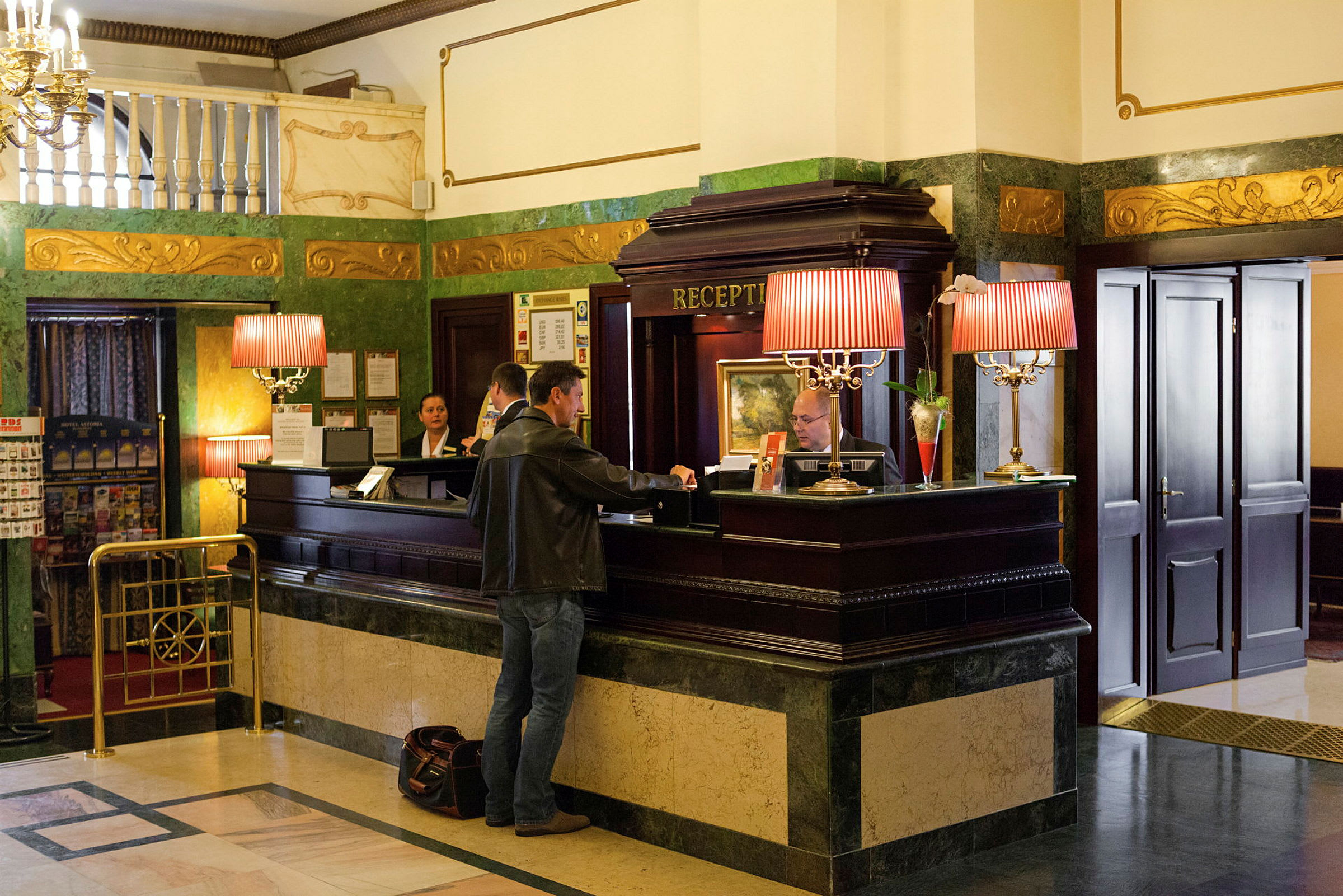 En resepsjonsdisk på hotell med en gjest og ansatte i samtale. (AI-generert tekst)