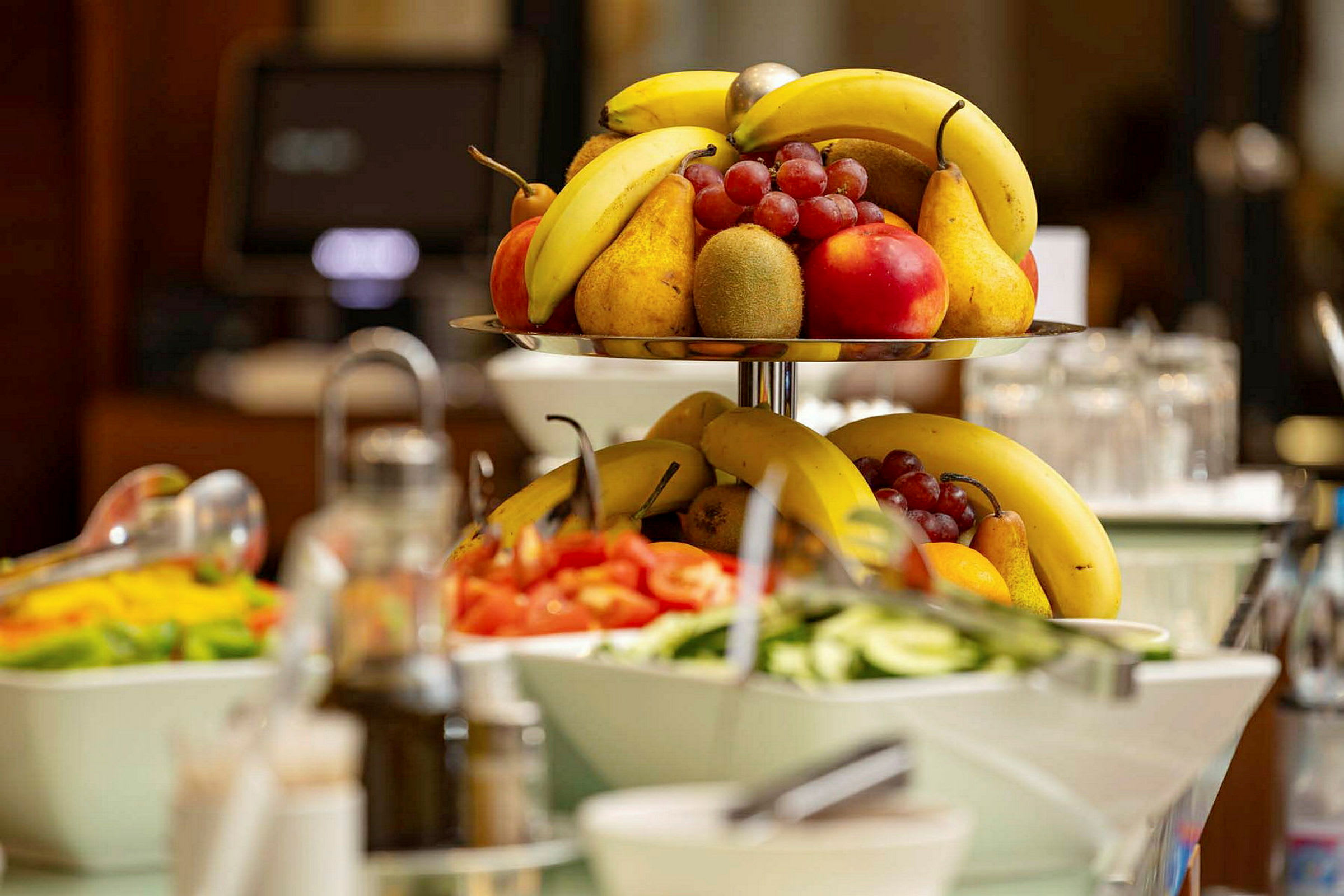 Et fruktfat med bananer, druer, pærer og epler står fremme sammen med boller med grønnsaker. (AI-generert tekst)