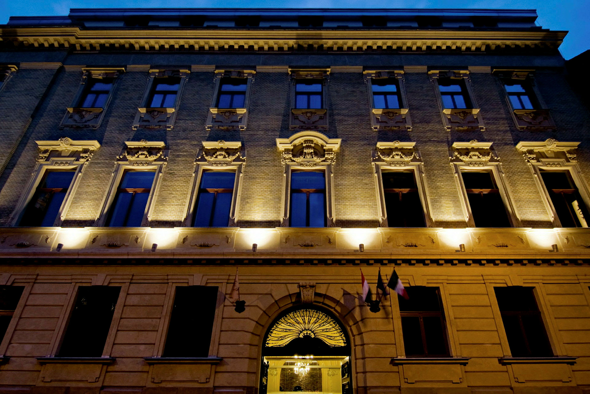 Bygningens fasade med belyste vinduer og detaljert arkitektur. (AI-generert tekst)