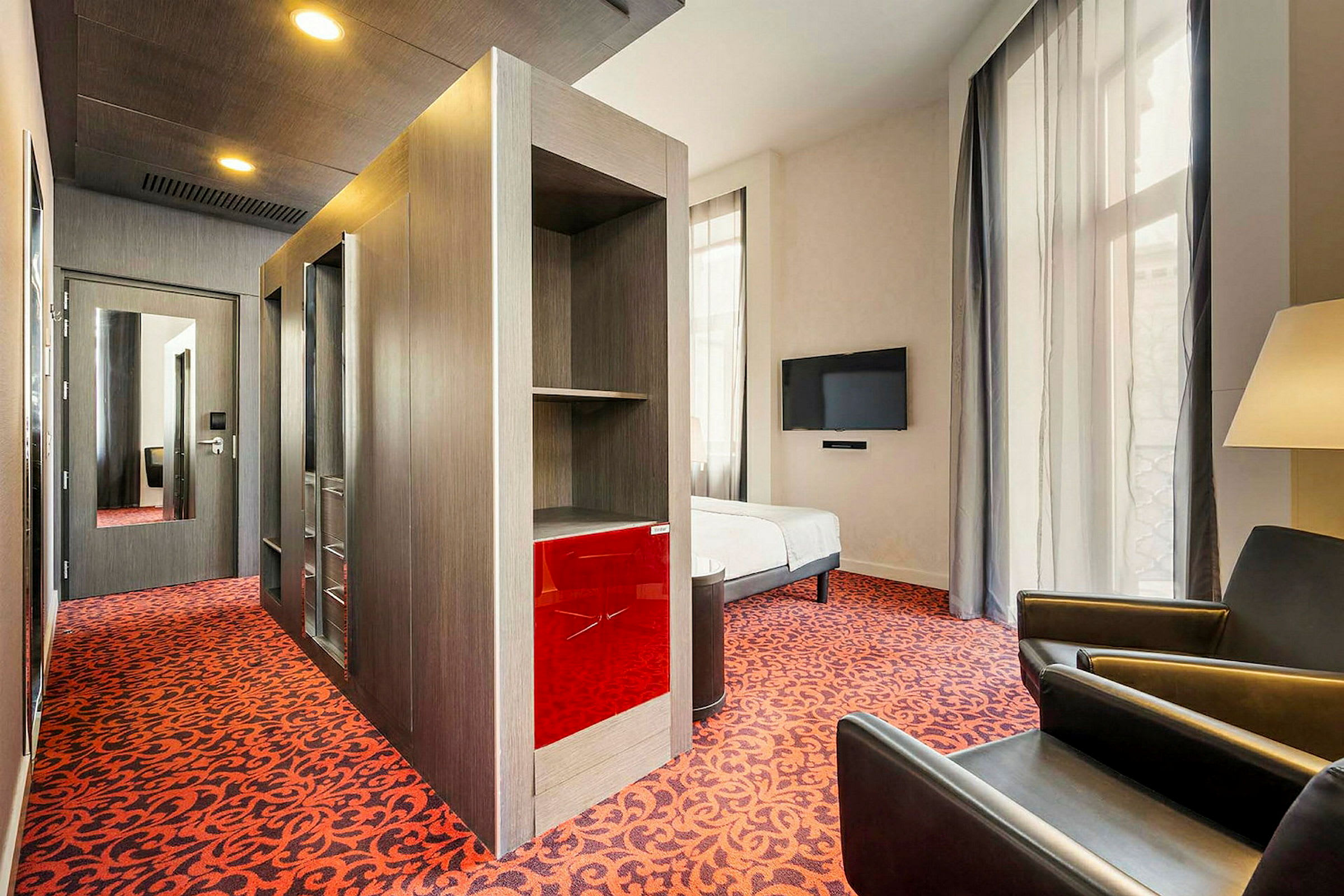 Hotellrom med moderne innredning, et rødt teppe og en veggmontert TV. (AI-generert tekst)