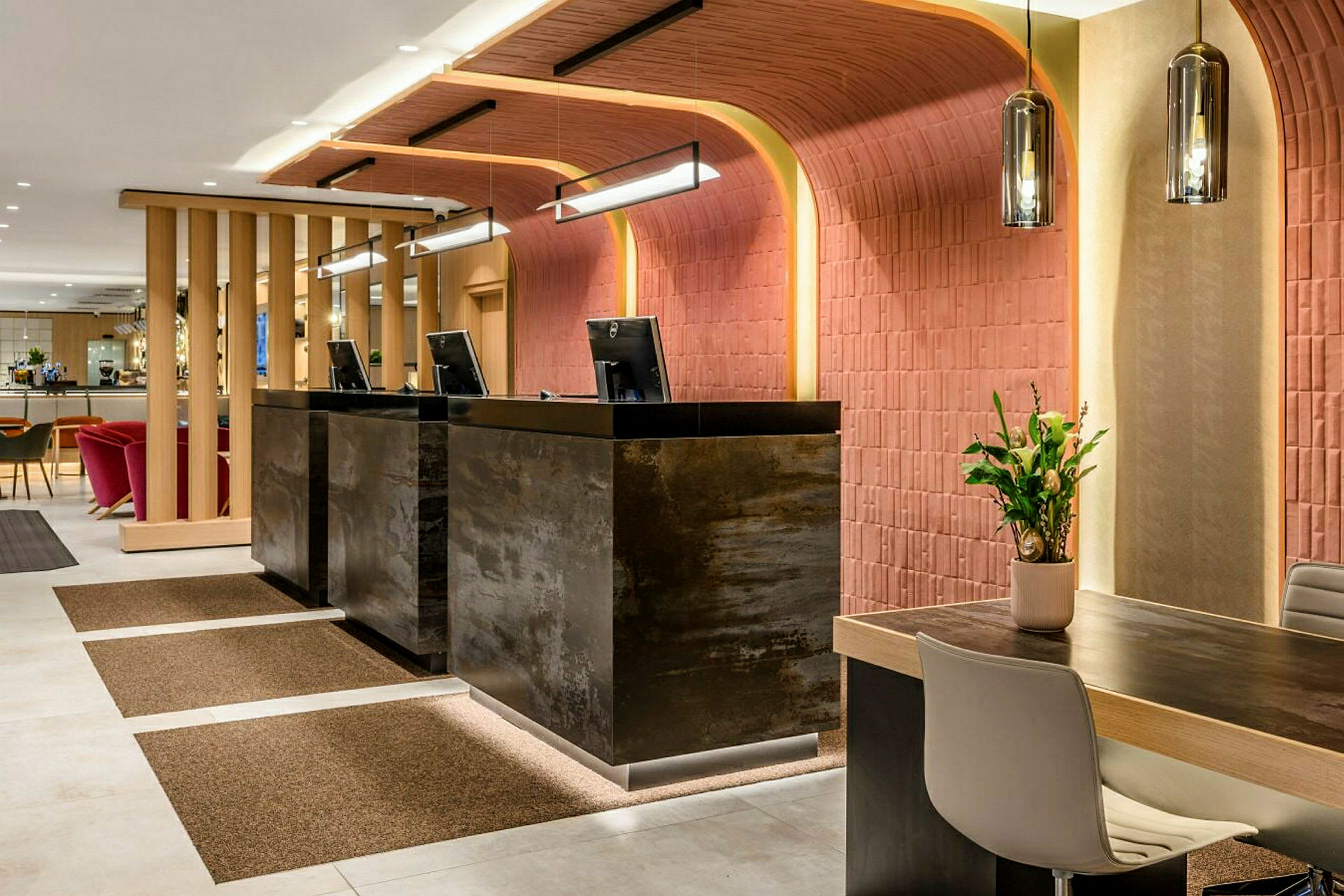Resepsjonen på et hotell med moderne møbler og innredning, tre disker med datamaskiner og en sittegruppe i bakgrunnen. (AI-generert tekst)