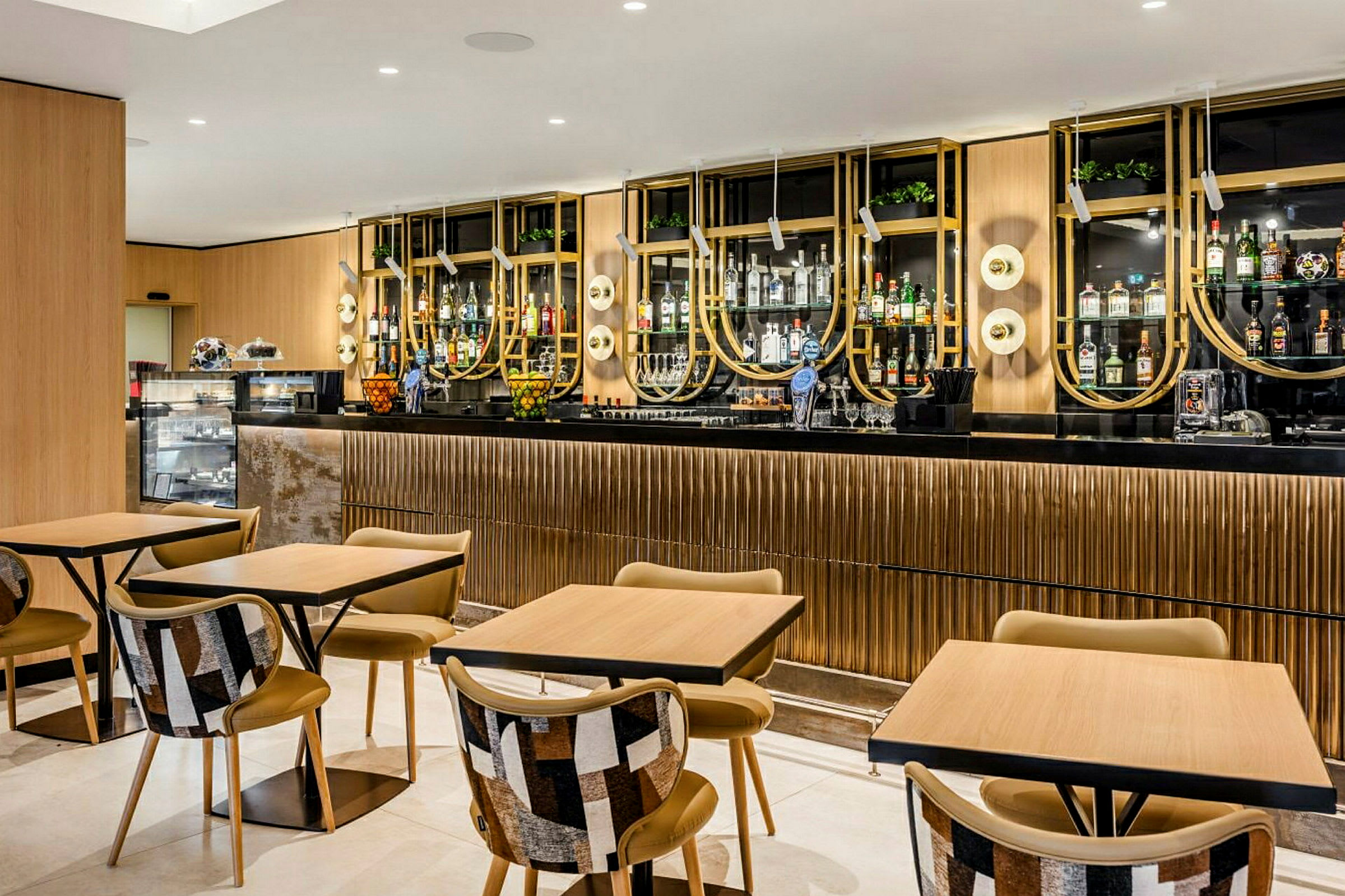 En moderne bar og kafé med stilige bord og stoler, samt en elegant og velorganisert drikkehylle i bakgrunnen. (AI-generert tekst)
