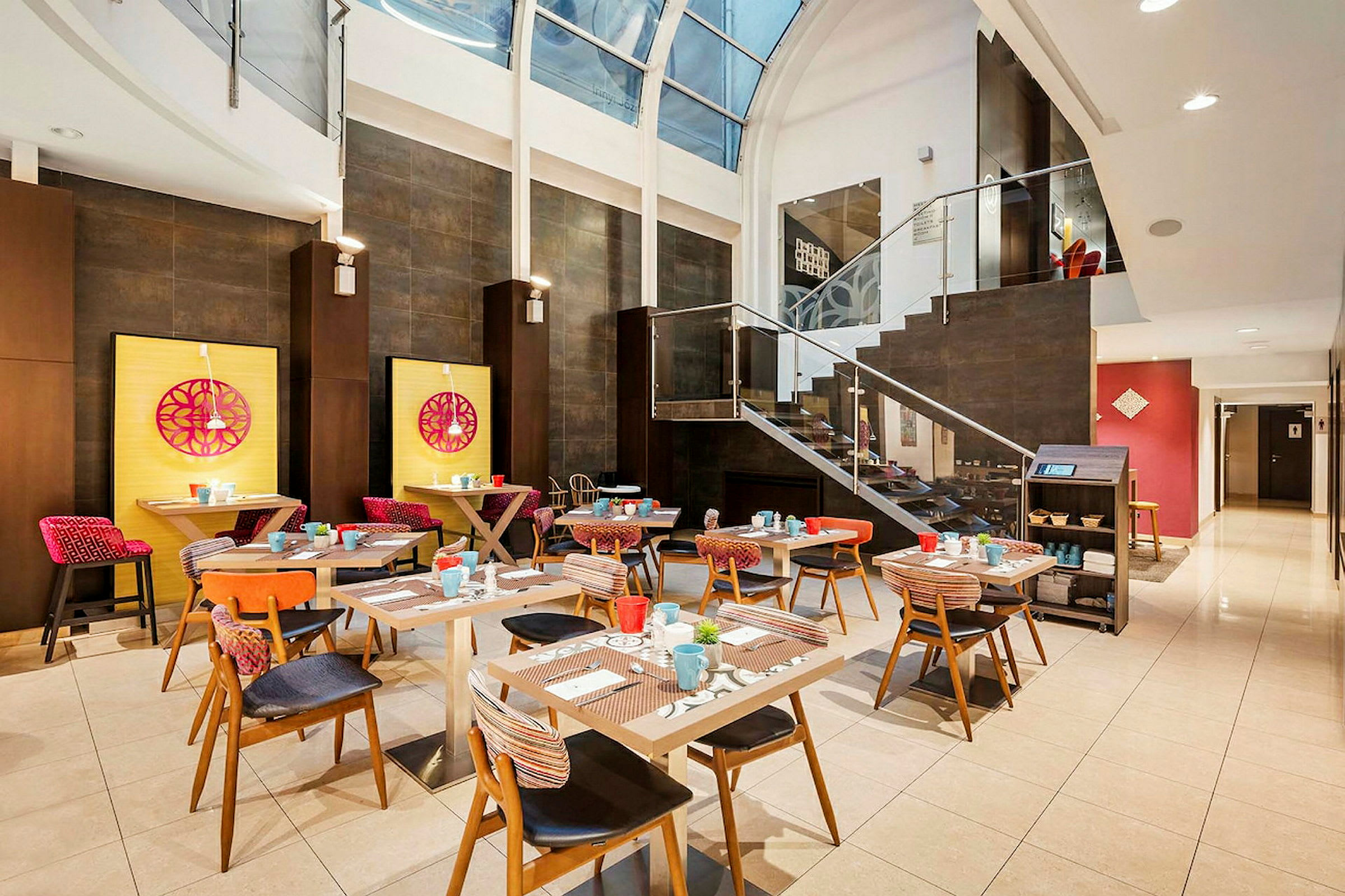 Et lyst og moderne restaurantmiljø med fargerike møbler og et stort glassvindu ovenfor. (AI-generert tekst)