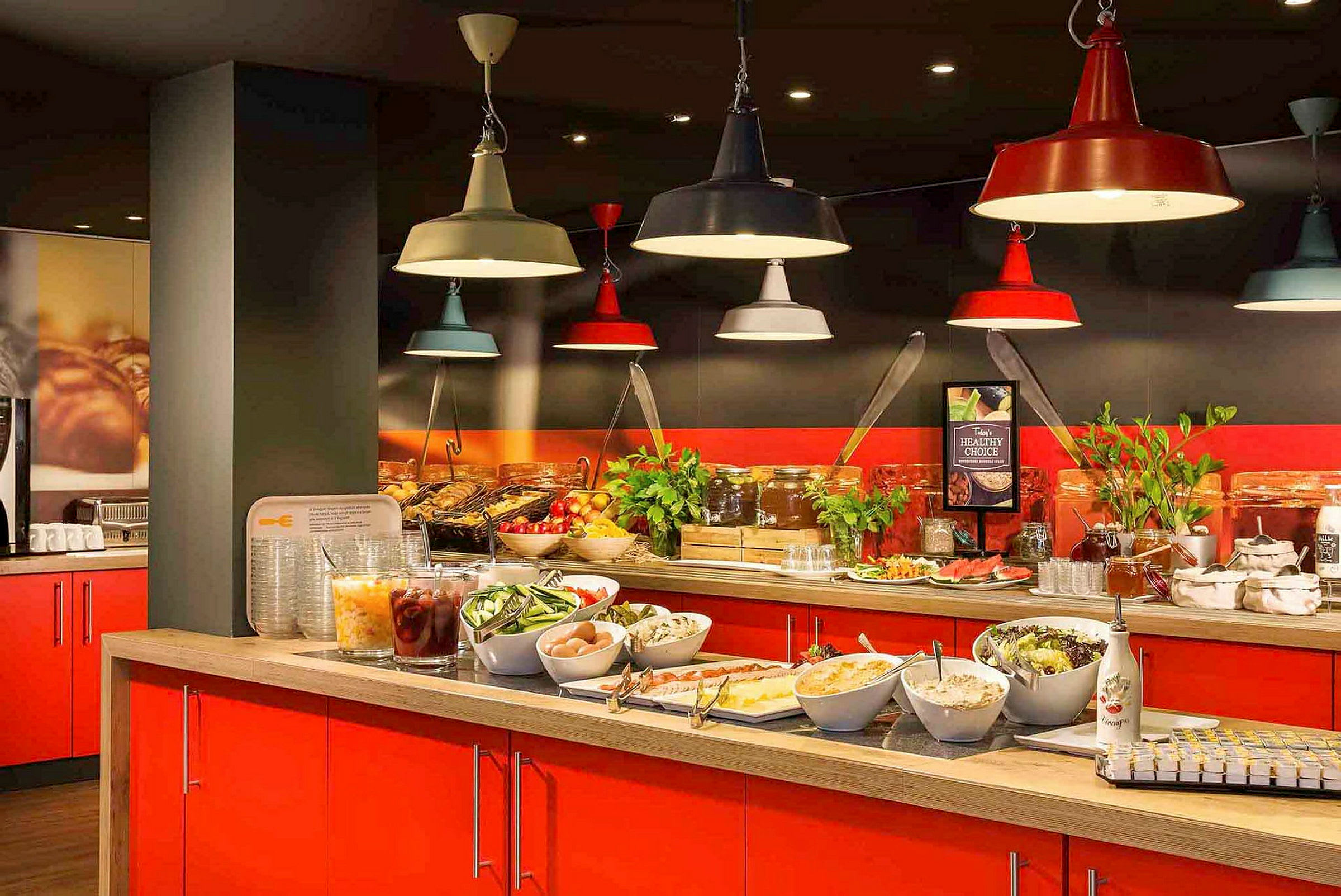 Buffetbord med salater, frukt og tilbehør, plassert under fargerike lamper. (AI-generert tekst)