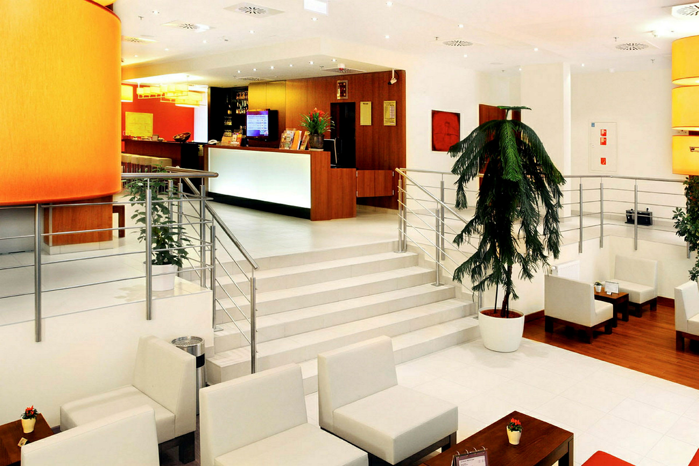 Lys og moderne hotellobby med resepsjon, sofaer, bord og dekorative planter. (AI-generert tekst)