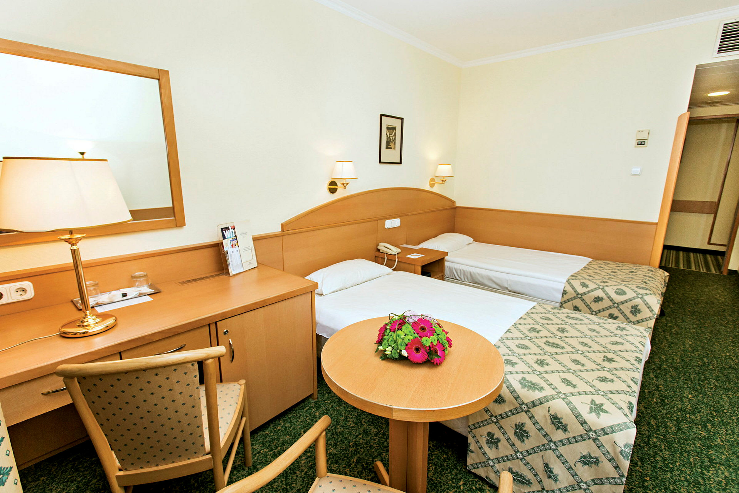 To enkeltsenger på et hotellrom med treinteriør og blomster på et bord. (AI-generert tekst)