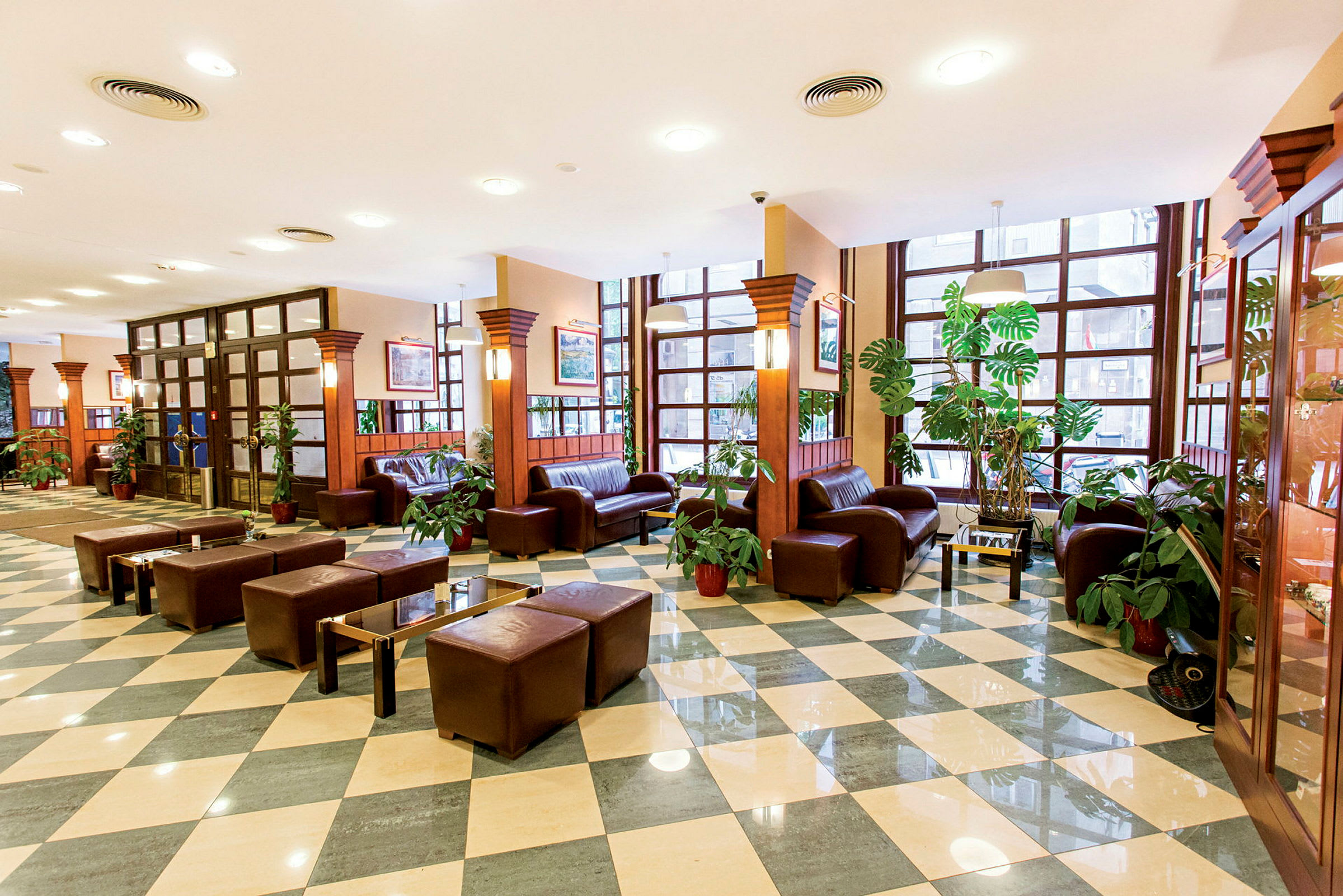 Hotellobby med brune skinnmøbler og grønne planter. (AI-generert tekst)