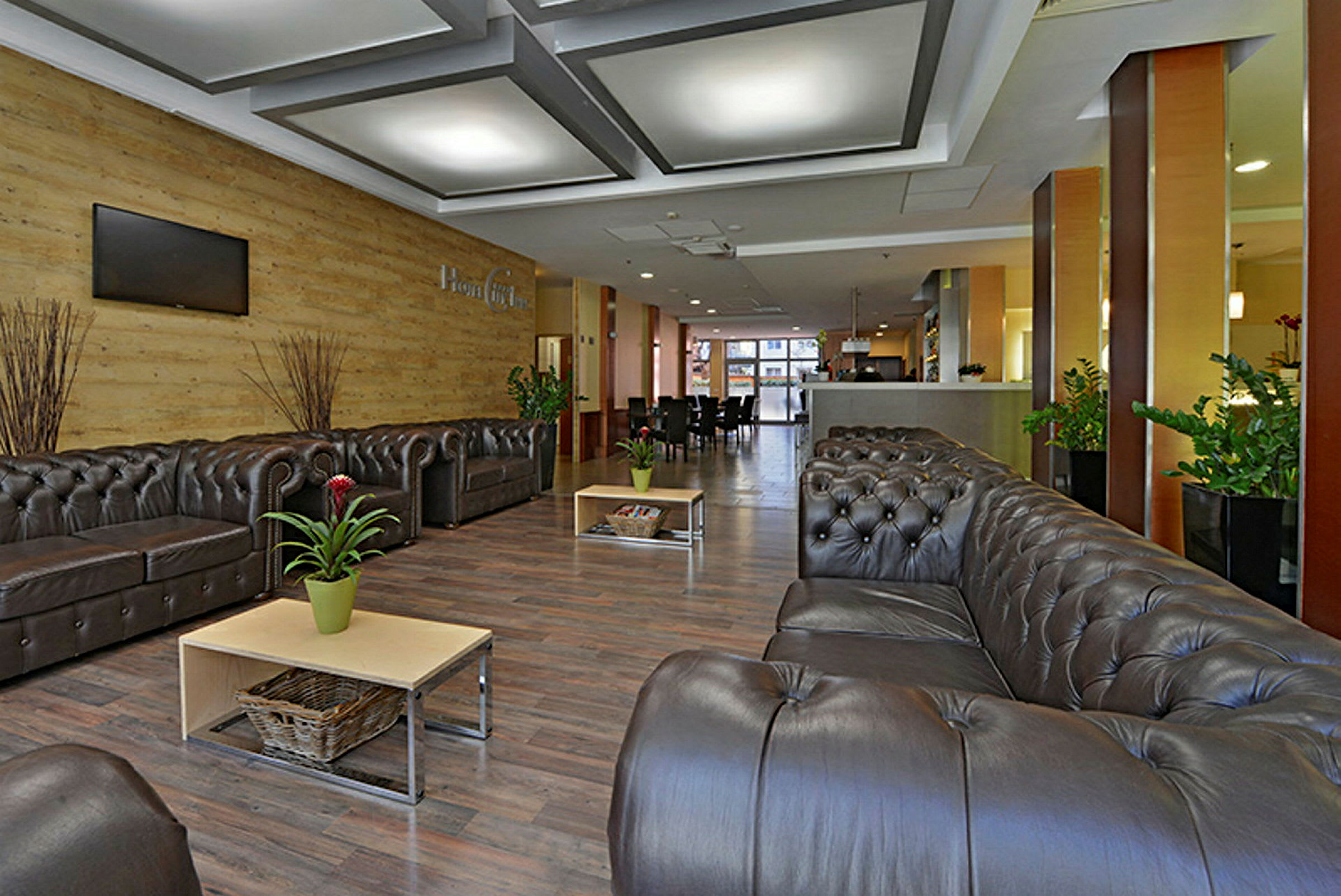 En hotellobby med komfortable sofaer, sofabord, potteplanter og moderne interiør. (AI-generert tekst)