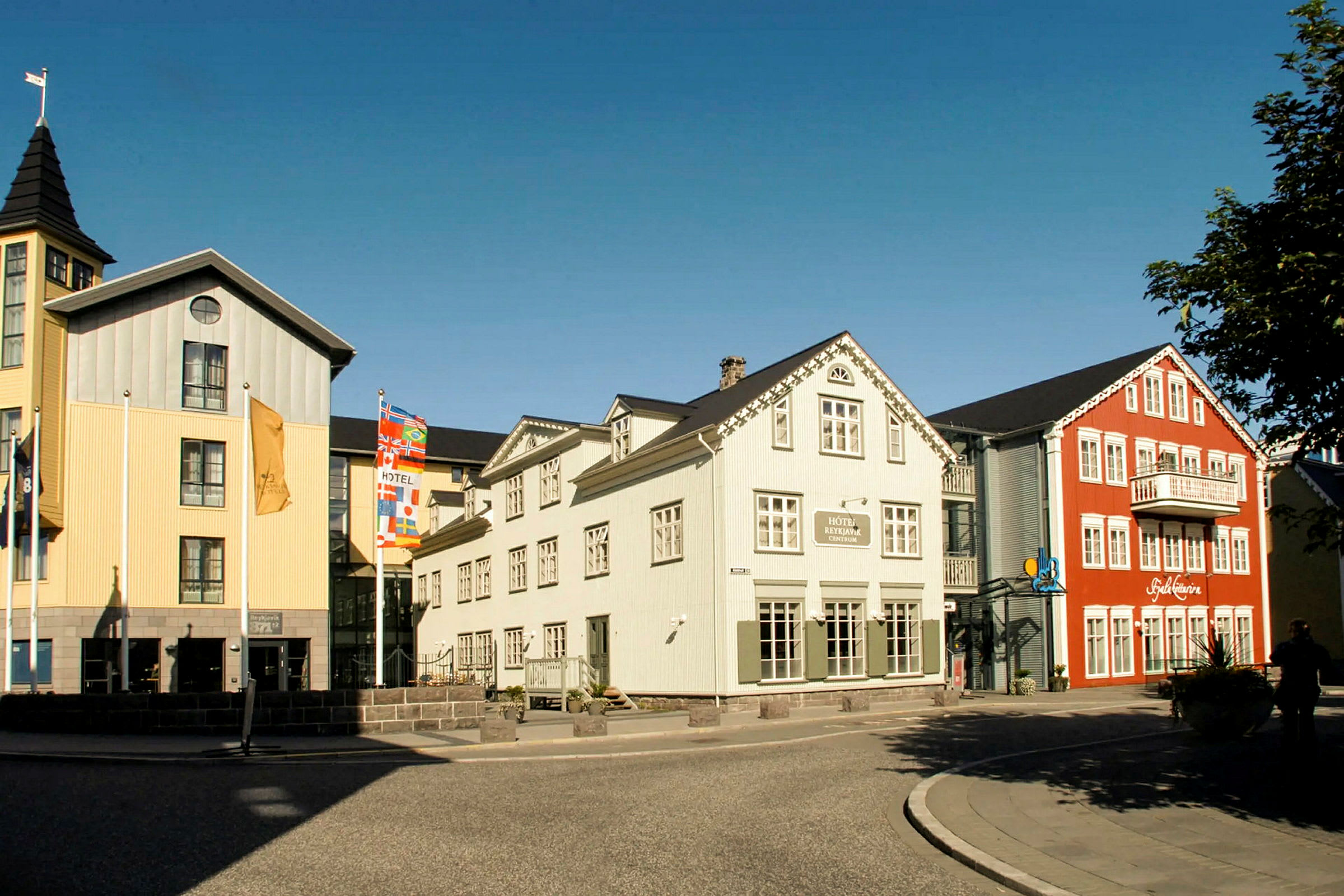 Bilde av fargerike bygninger med hotell og restaurant nær en gate med fortau. (AI-generert tekst)