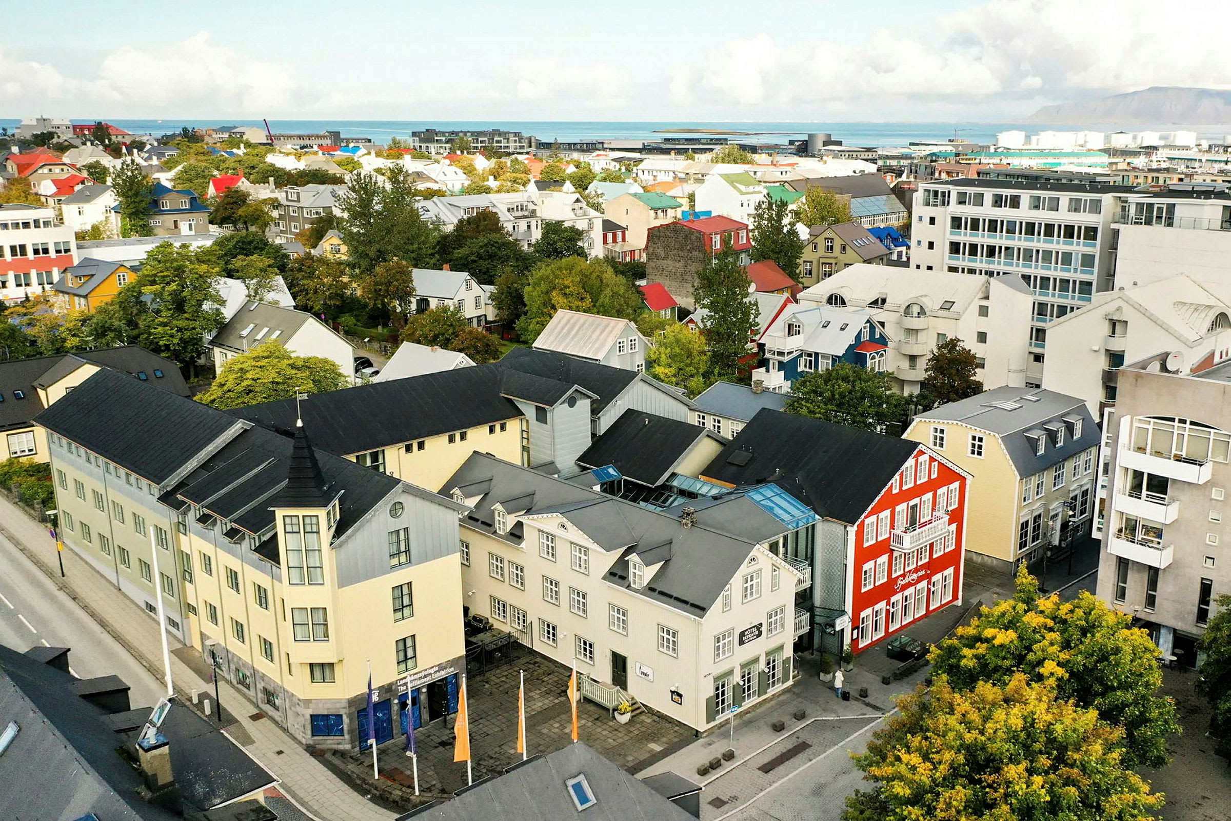 Flyfoto av en by med fargerike bygninger og grøntområder. (AI-generert tekst)