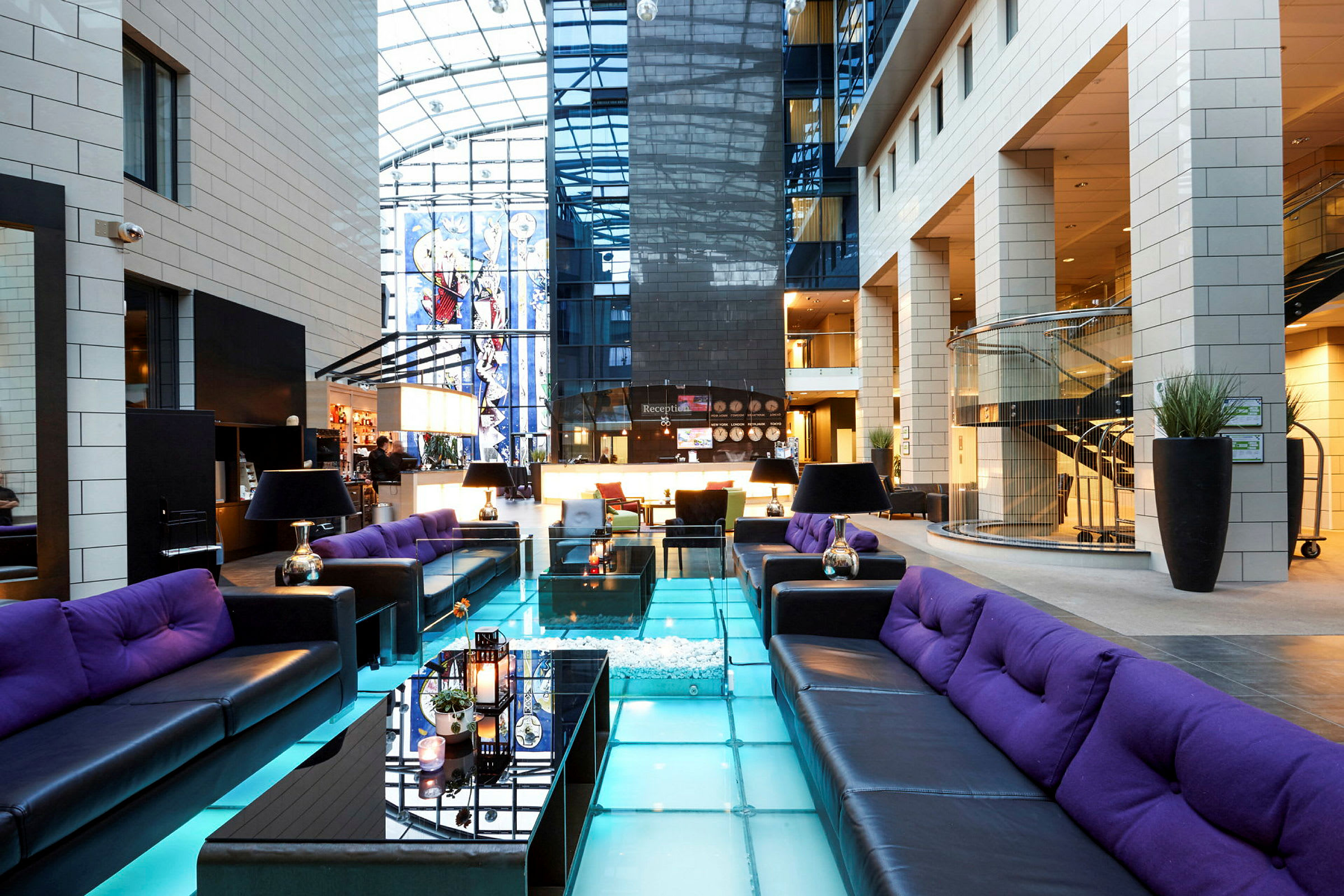 En moderne hotellobby med sittegrupper og glassgulv. (AI-generert tekst)
