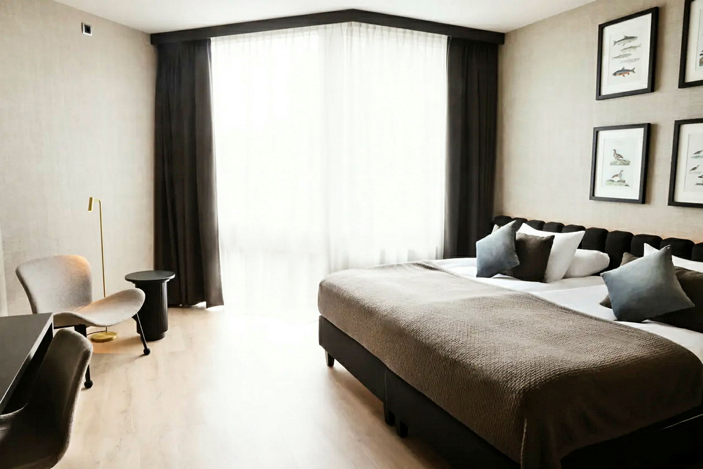 Et hotellrom med en dobbeltseng, sittemøbler og et stort vindu med lyse gardiner. (AI-generert tekst)