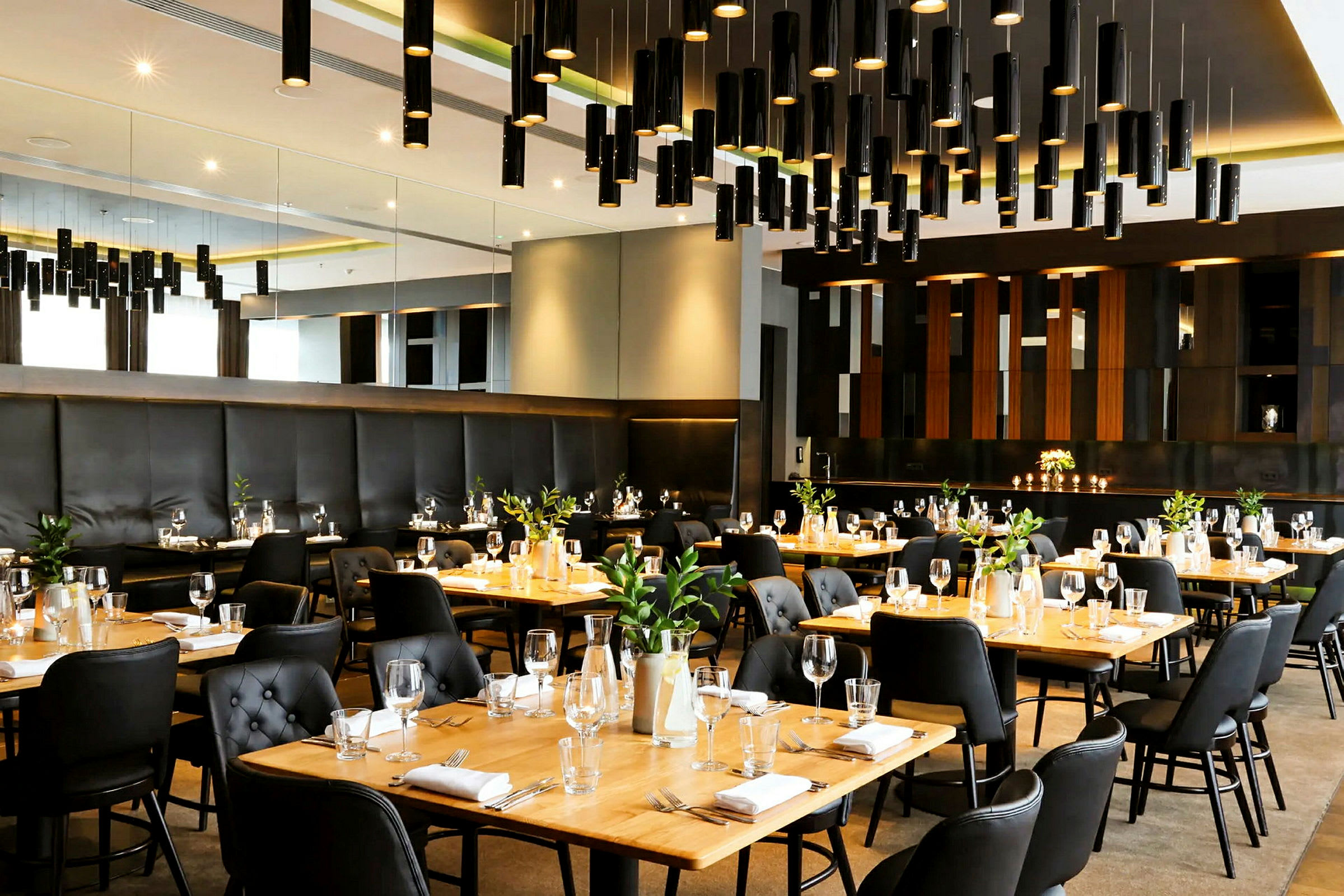 En elegant restaurant med dekkede bord, svarte stoler og trebord, og moderne belysningsdesign. (AI-generert tekst)