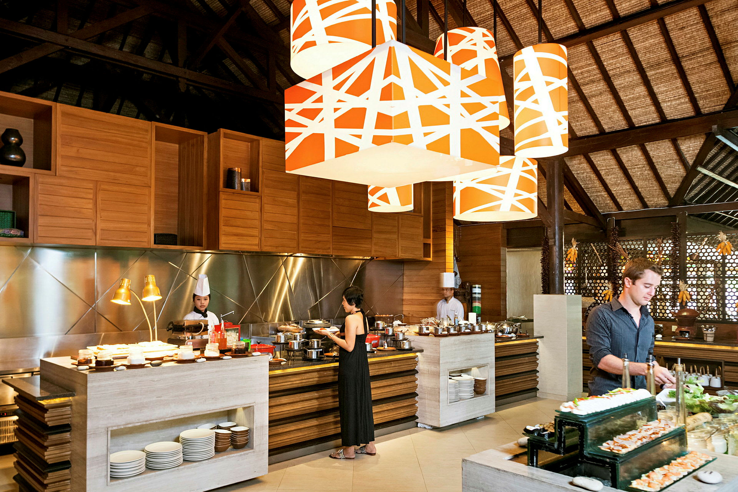 Et interiør av en restaurant med en buffet, store oransje taklamper og en rustikk treinnredning. (AI-generert tekst)