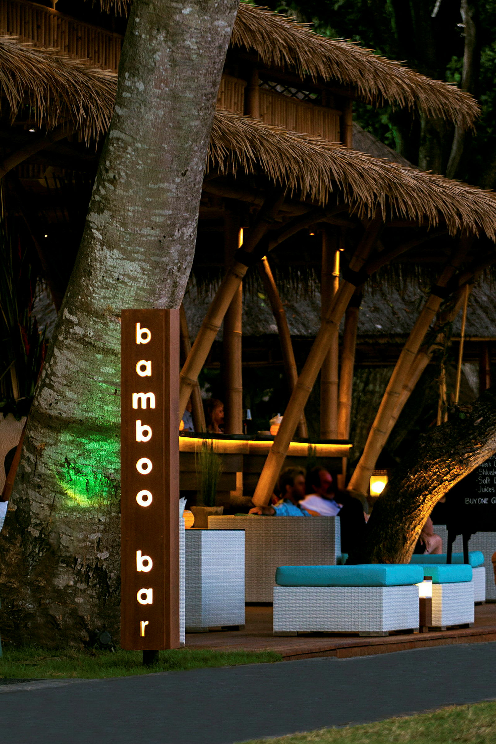 En bar med et skilt som sier "bamboo bar" og en interiør med bambusstruktur og sittegrupper. (AI-generert tekst)