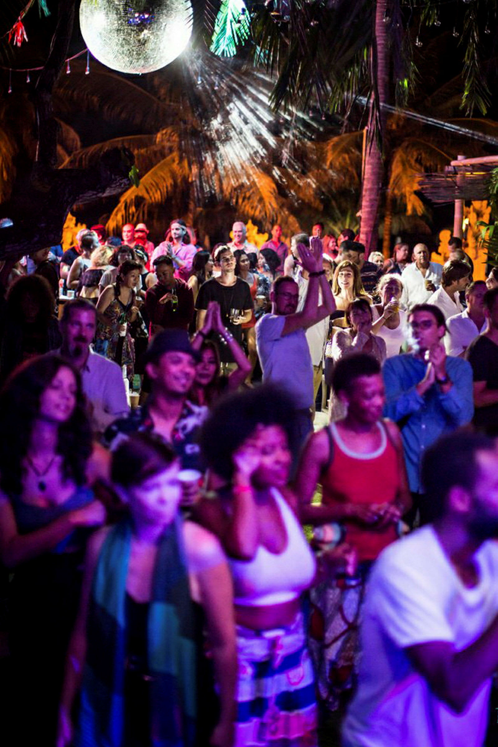 En utendørs nattklubbmiljø med folk som danser og en diskokule i bakgrunnen. (AI-generert tekst)