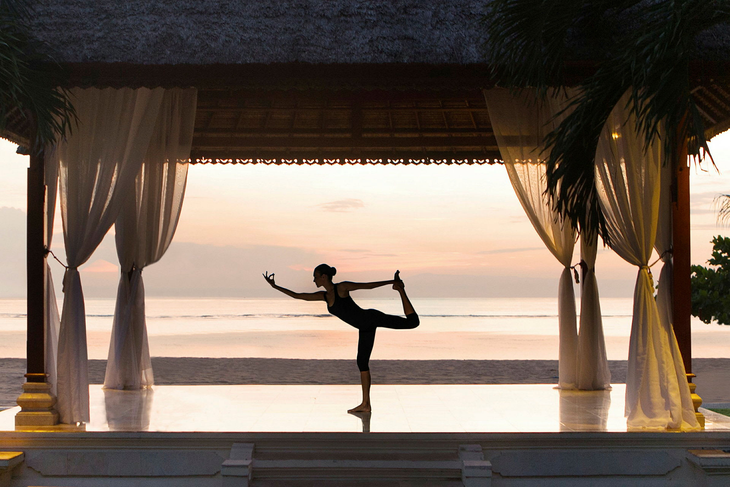 En person praktiserer yoga på en paviljong ved stranden med en beroligende horisont i bakgrunnen. (AI-generert tekst)