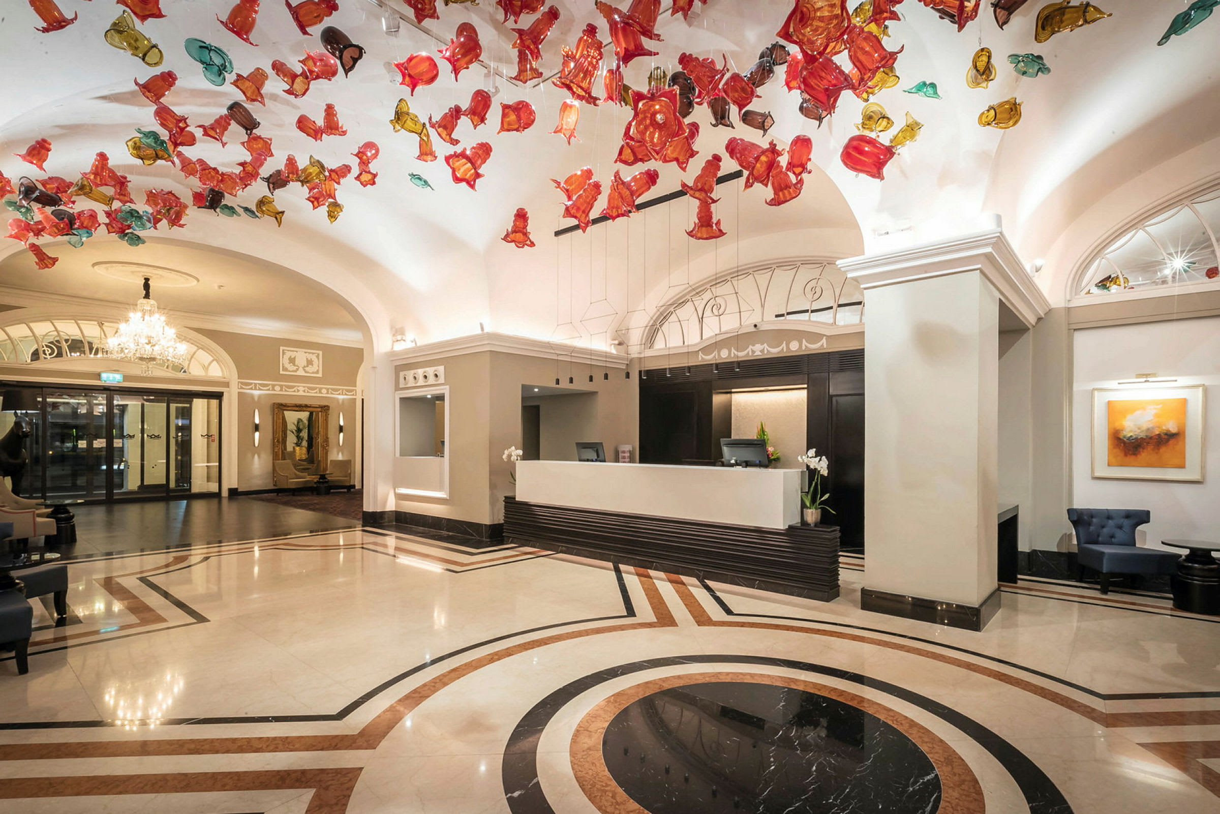 Hotellobby med resepsjon og fargerike dekorasjoner i taket. (AI-generert tekst)