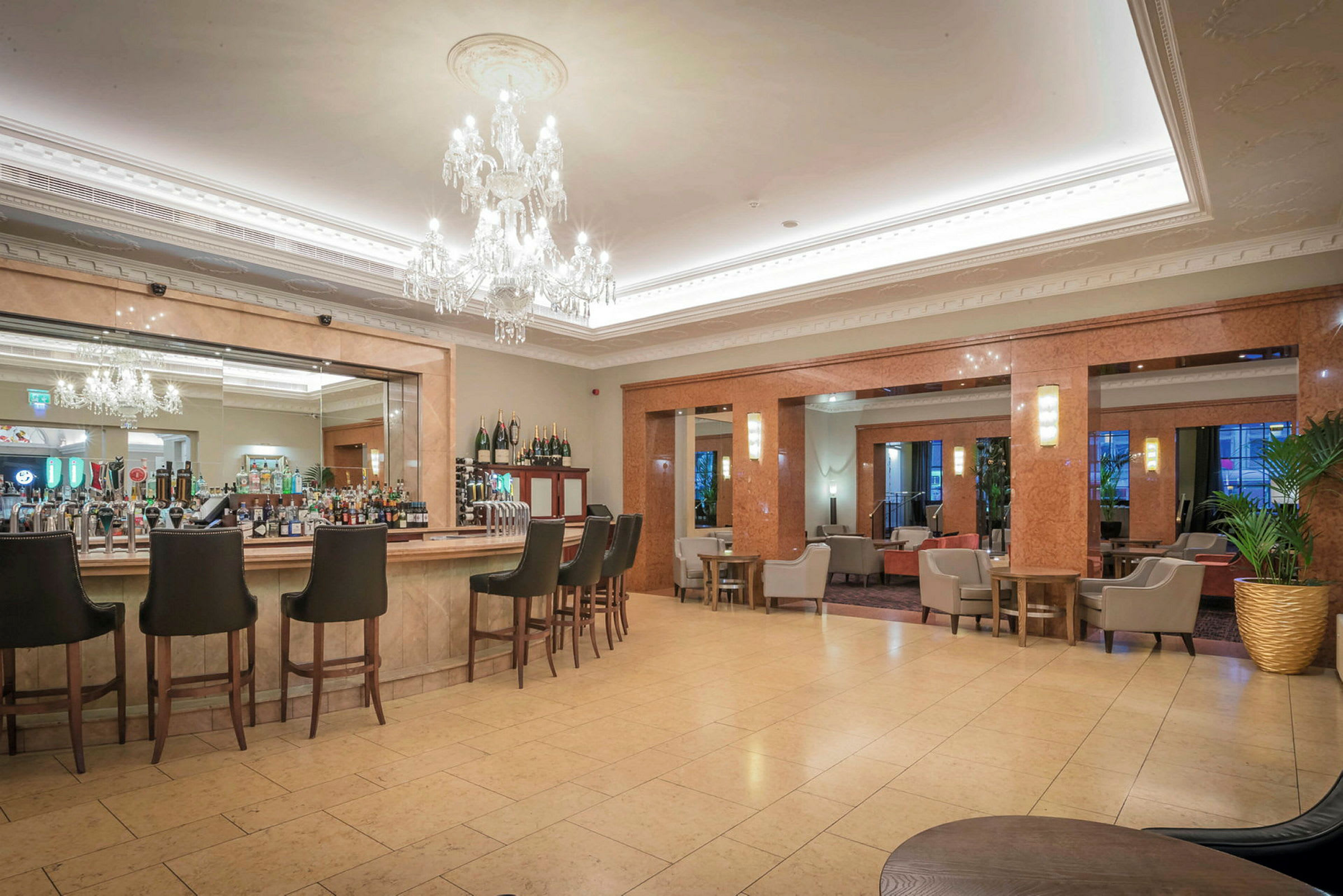 Moderne hotellbarområde med høye stoler og lysekroner. (AI-generert tekst)
