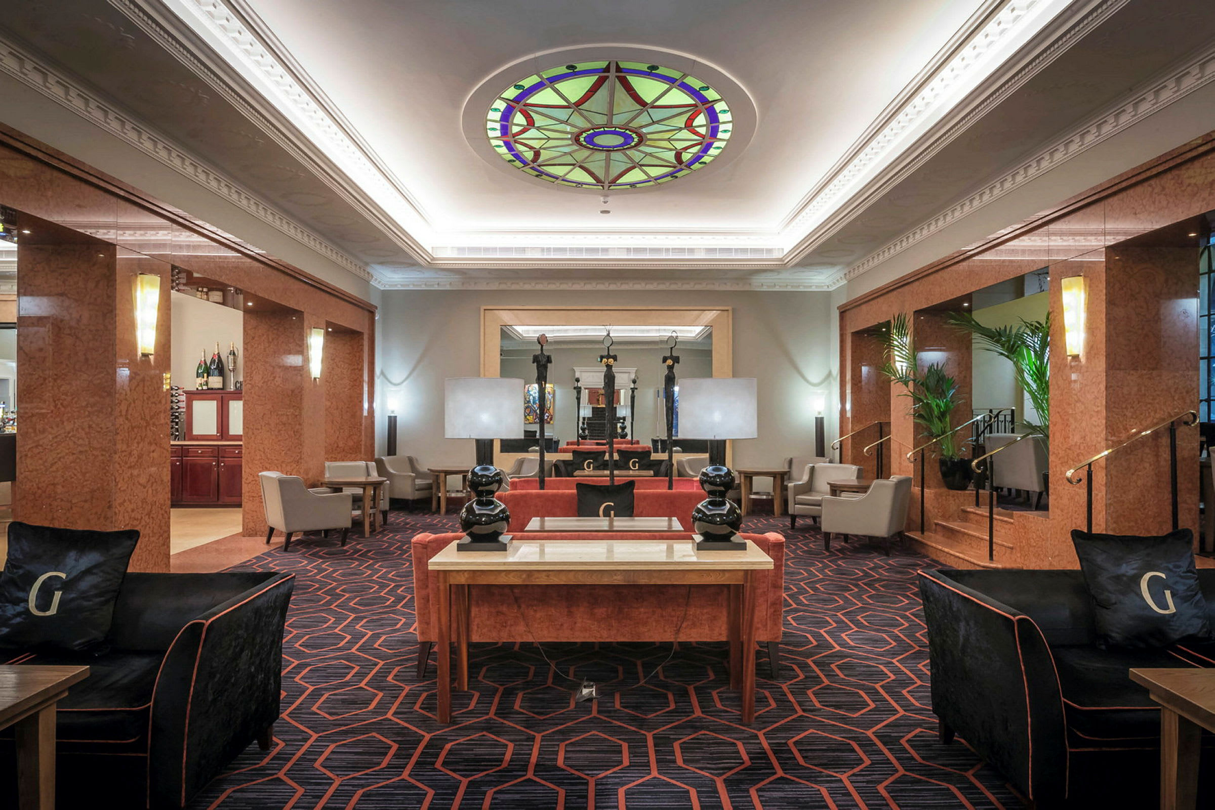 En hotellobby med komfortable møbler og dekorativt glasstak. (AI-generert tekst)