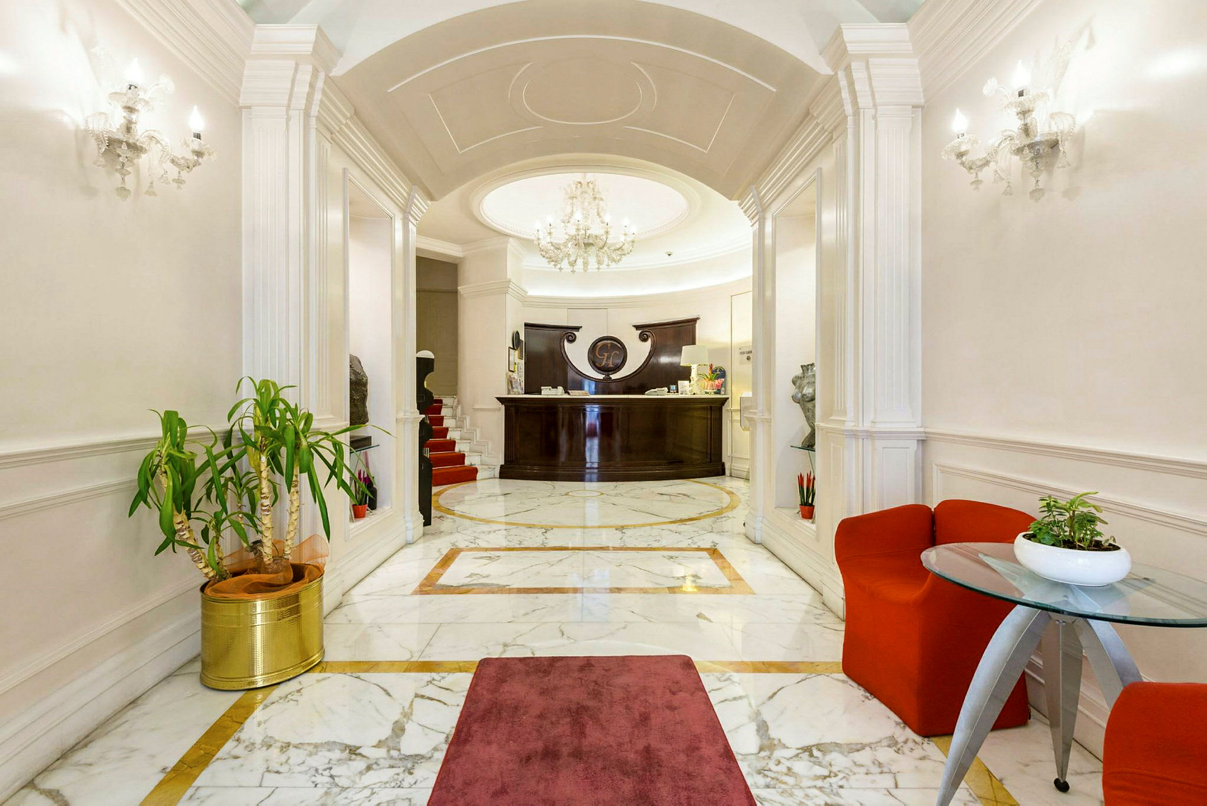 En elegant hotellobby med marmorgulv, en resepsjon i mørkt treverk og en stilig lysekrone. (AI-generert tekst)