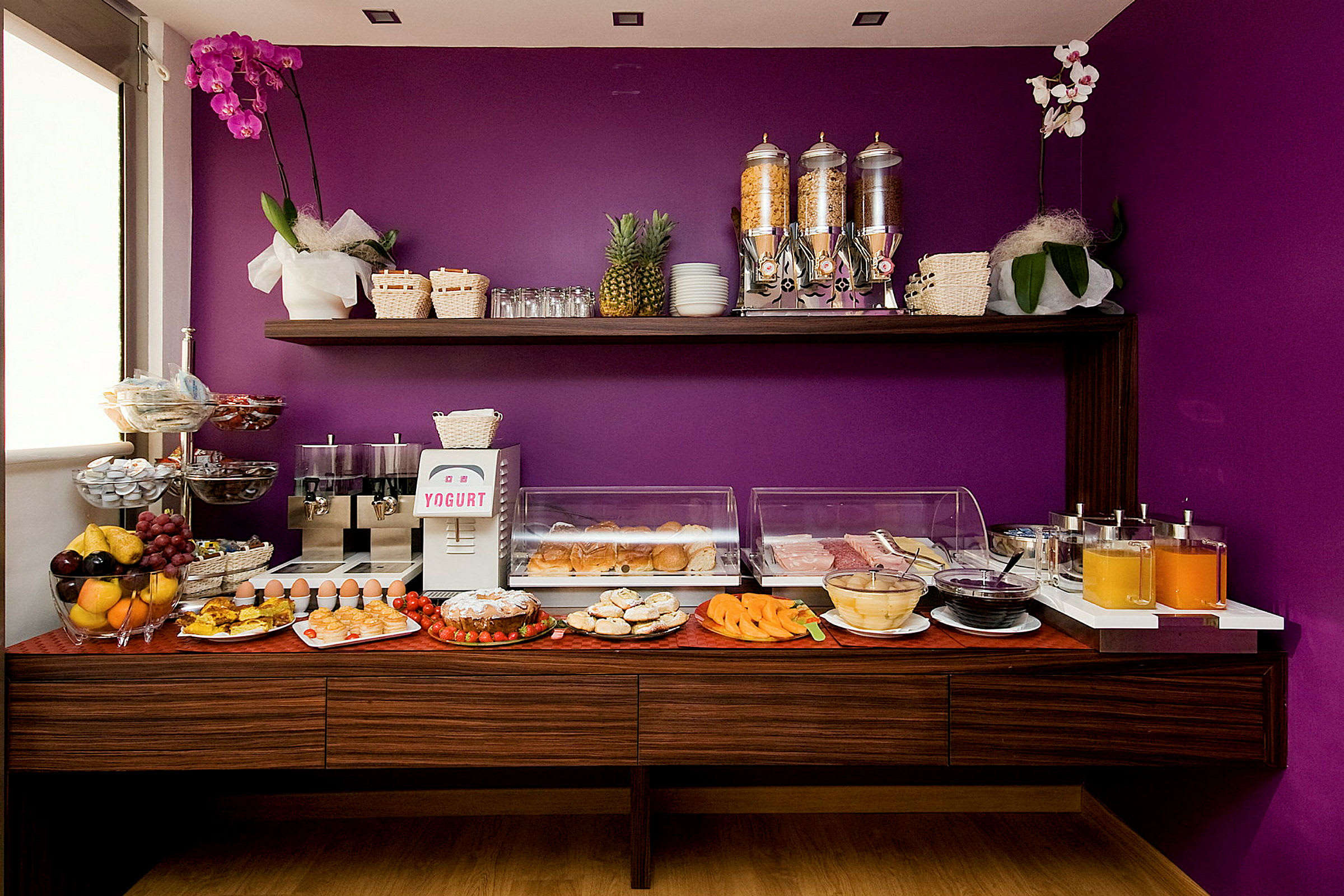 Buffet med frokostmat og drikke mot en lilla bakgrunn. (AI-generert tekst)