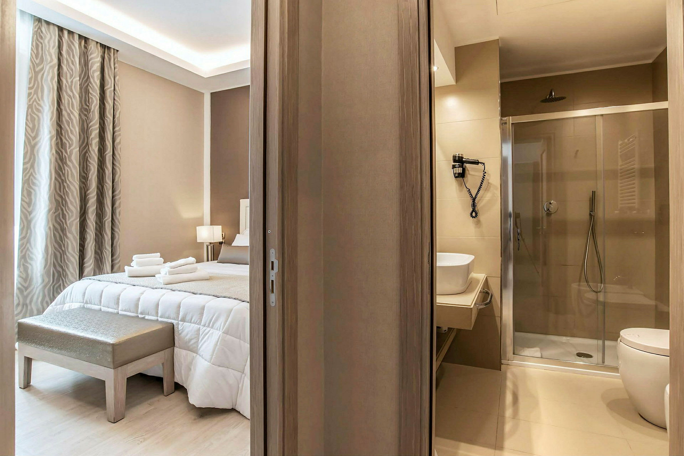 Hotellrom med en bred seng, innredet i lyse toner, ved siden av et moderne bad. (AI-generert tekst)