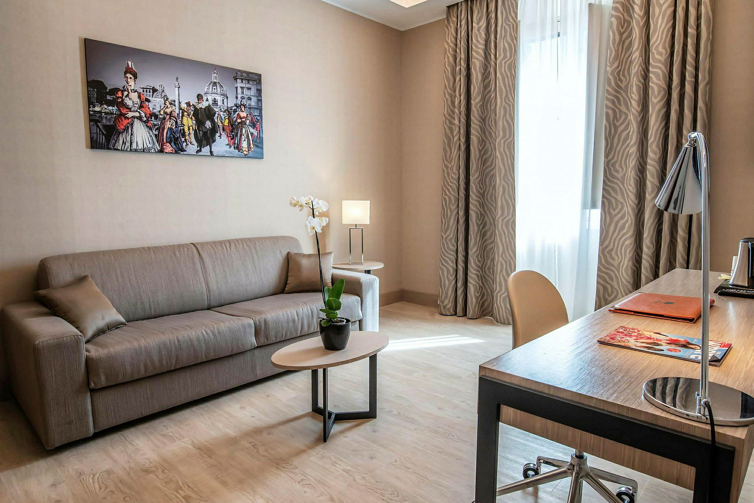 Et velmøblert stue med sofa og skrivebord, innredet med bilder og planter. (AI-generert tekst)