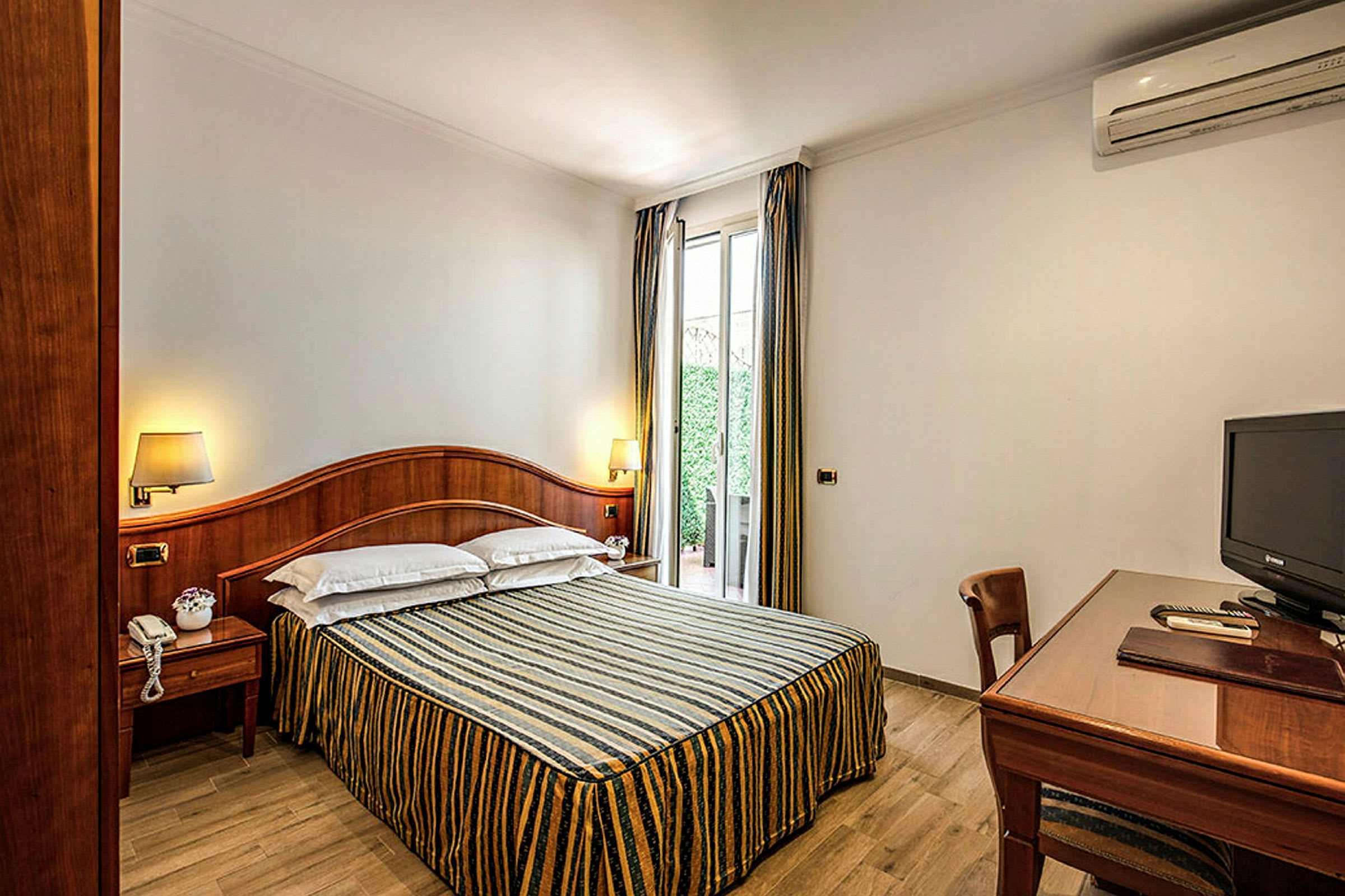 Et hotellrom med en dobbeltseng, et skrivebord og en TV. (AI-generert tekst)