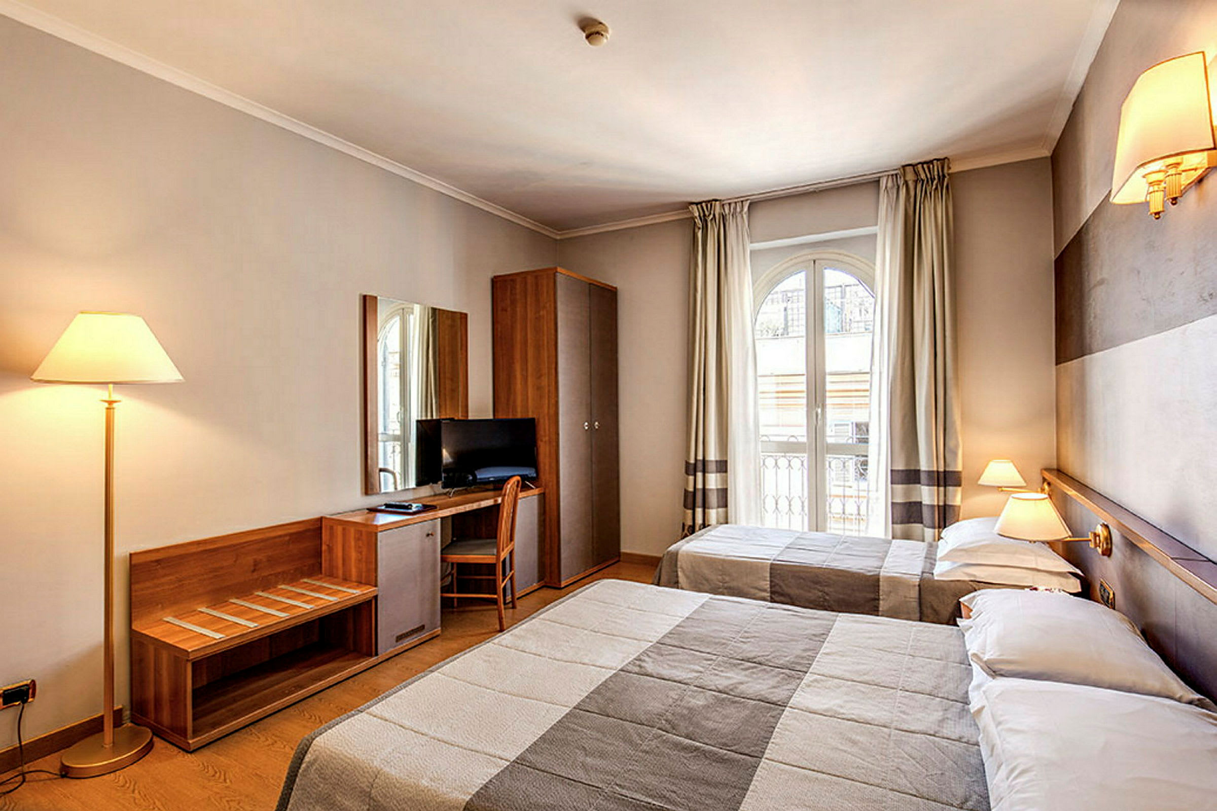 Hotellrom med to senger, skrivebord med stol, TV og elegant innredning. (AI-generert tekst)