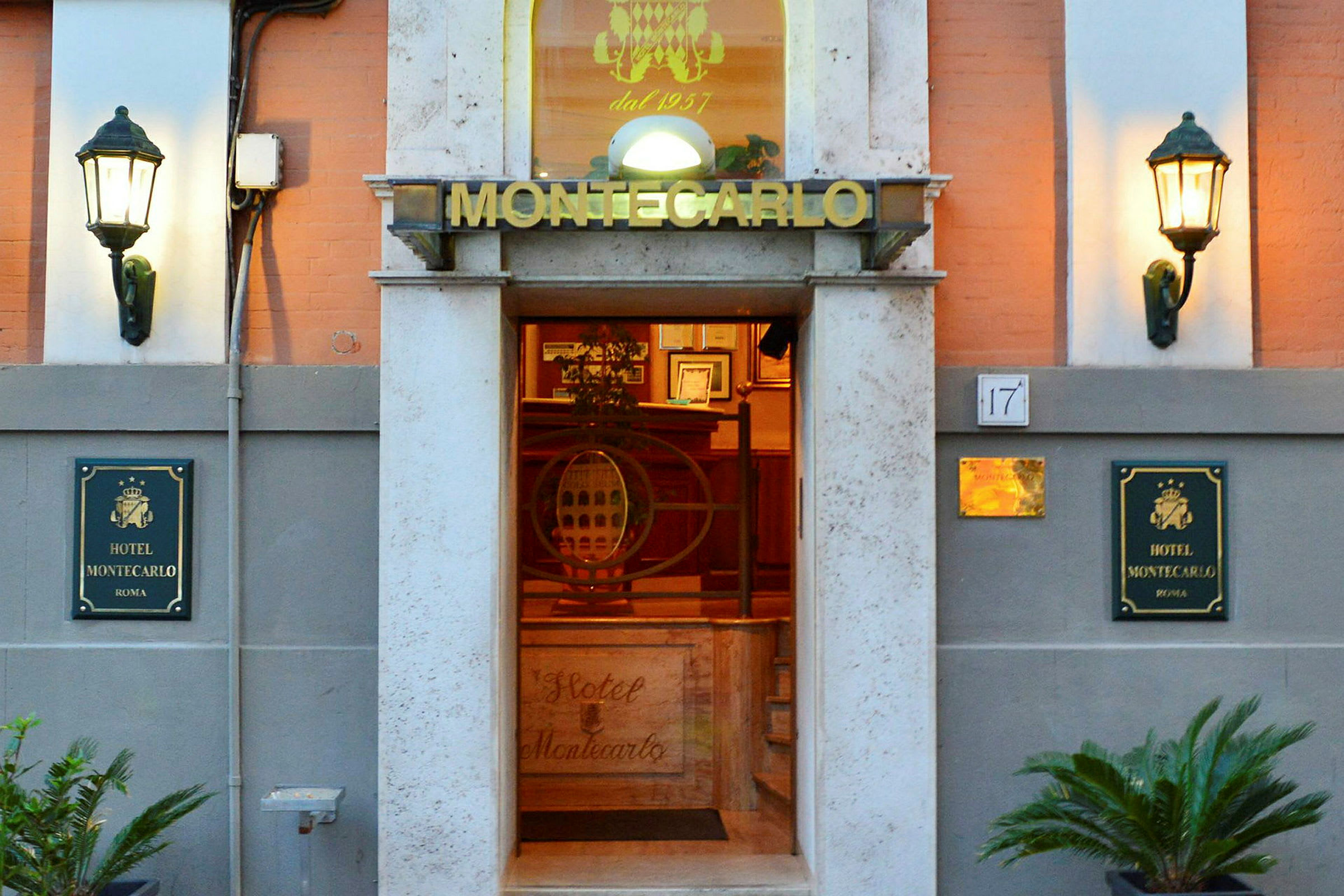 Inngangen til Hotel Montecarlo i Roma med skilt og belysning på begge sider av fasaden. (AI-generert tekst)