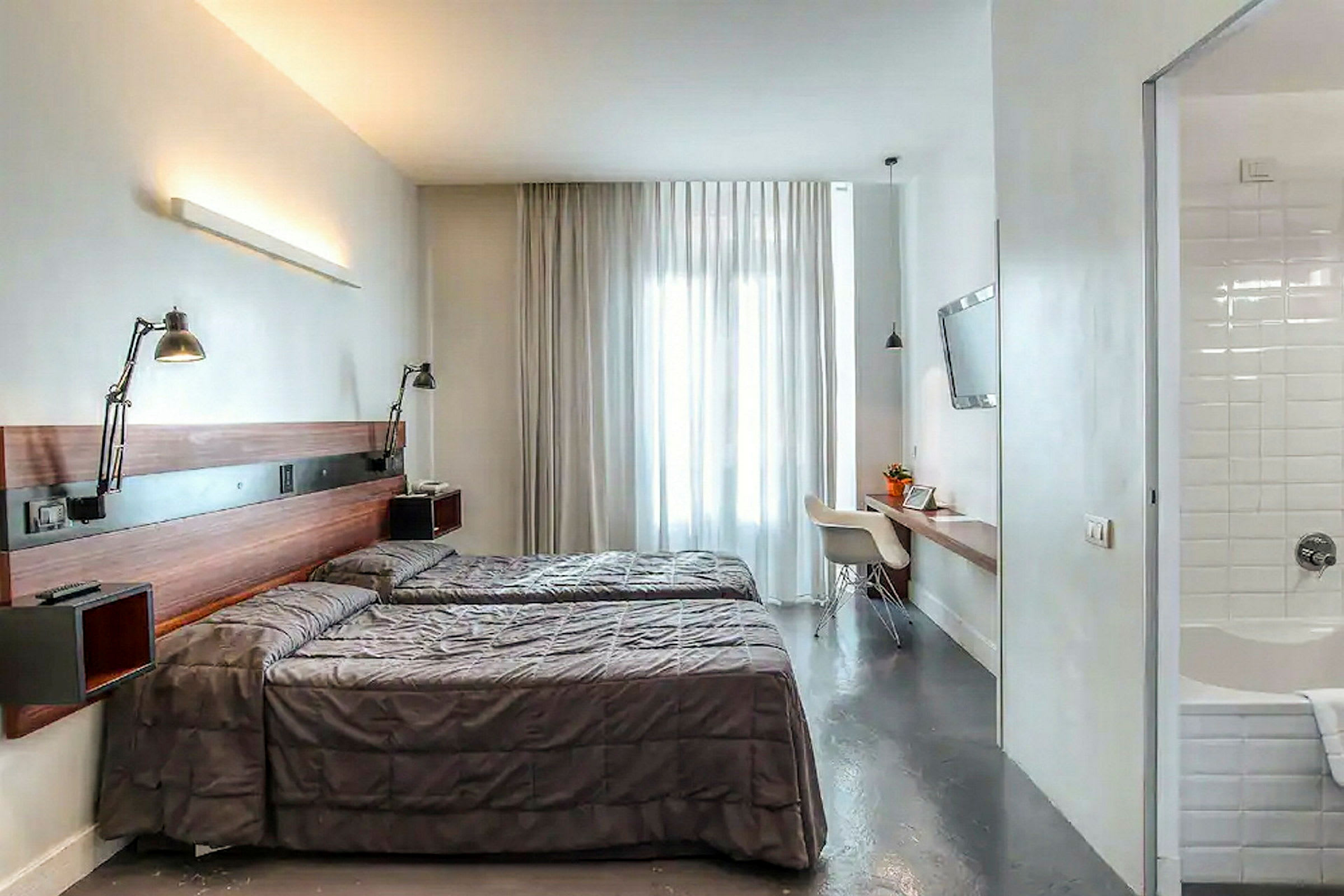 Hotellrom med to enkeltsenger, skrivebord og bad. (AI-generert tekst)