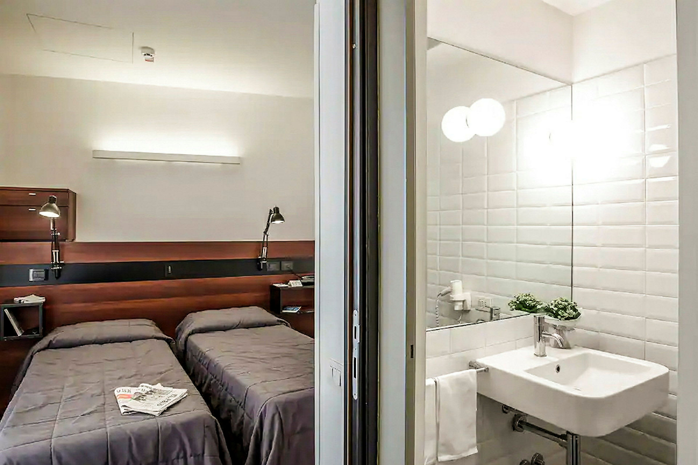 Hotellrom med to enkeltsenger og et tilstøtende bad. (AI-generert tekst)