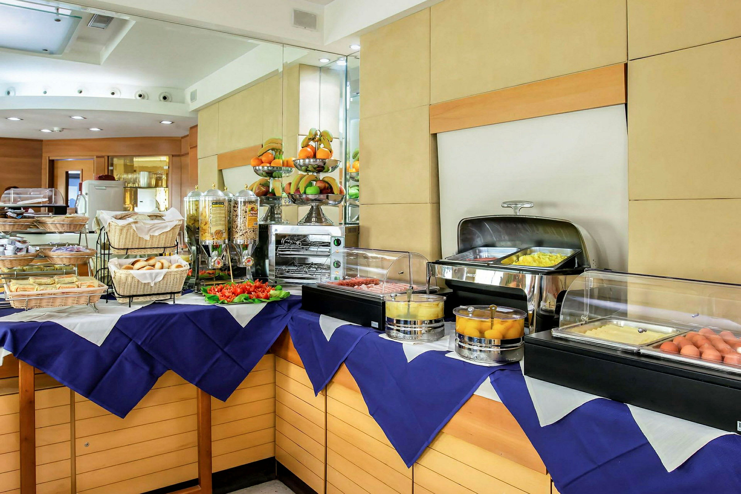 Buffet med ulike retter, inkludert frokostalternativer som brød, egg og frukt ordnet på et bord. (AI-generert tekst)