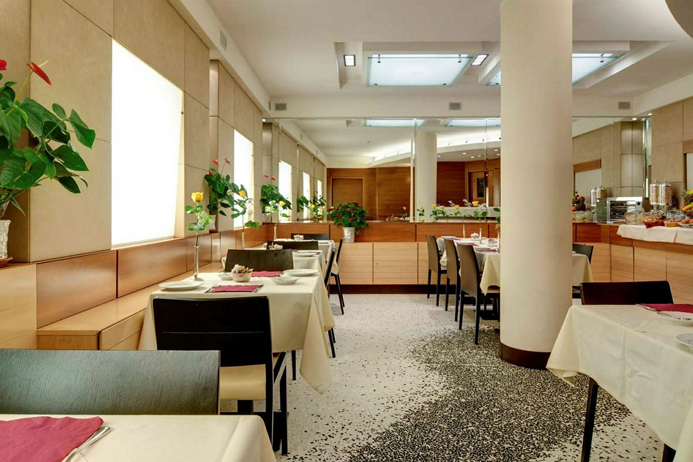 En moderne restaurant med oppsatte bord og blomster på hvert bord. (AI-generert tekst)