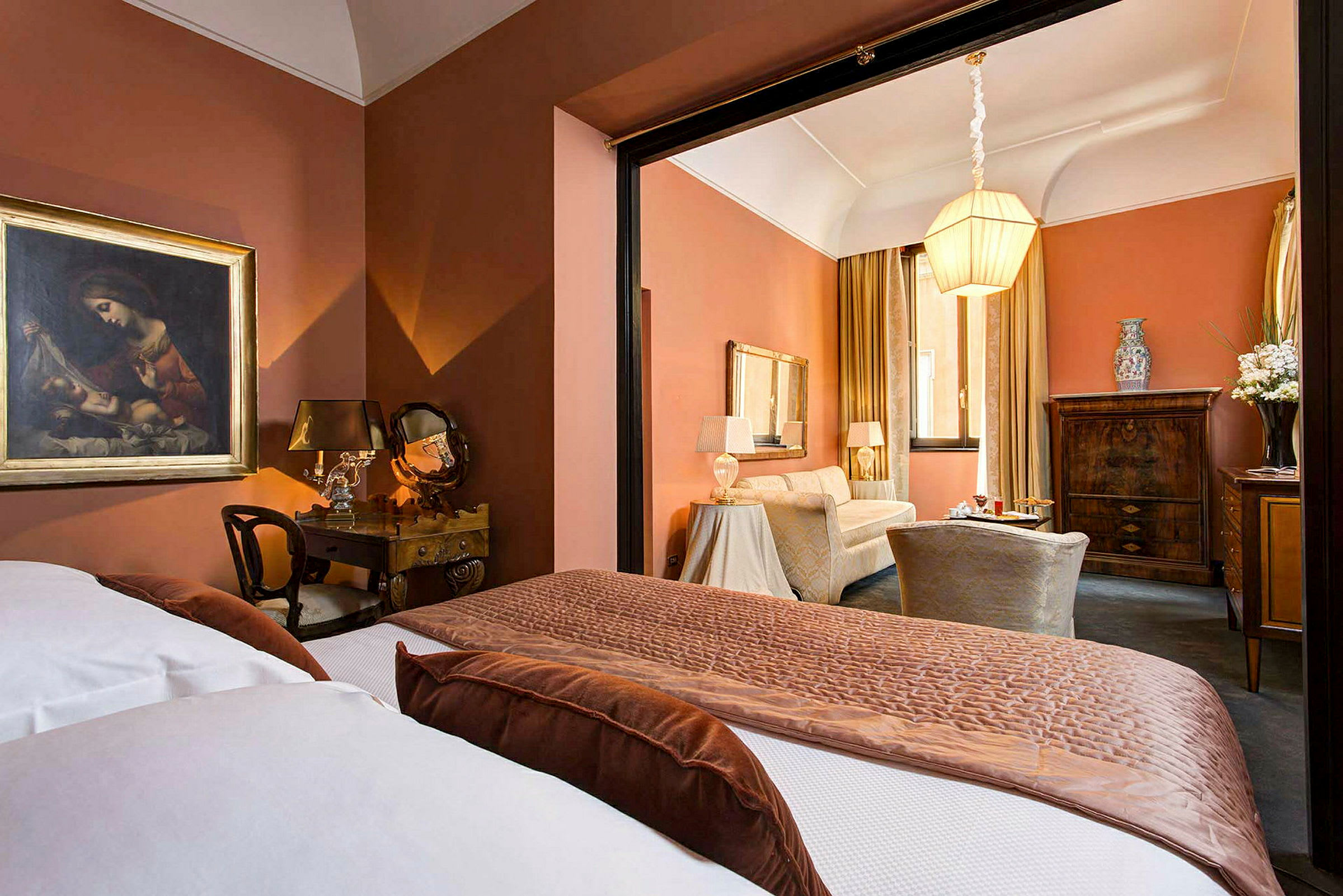 Et elegant hotellrom med varme oransje farger, klassisk innredning og en dobbeltseng i forgrunnen. (AI-generert tekst)
