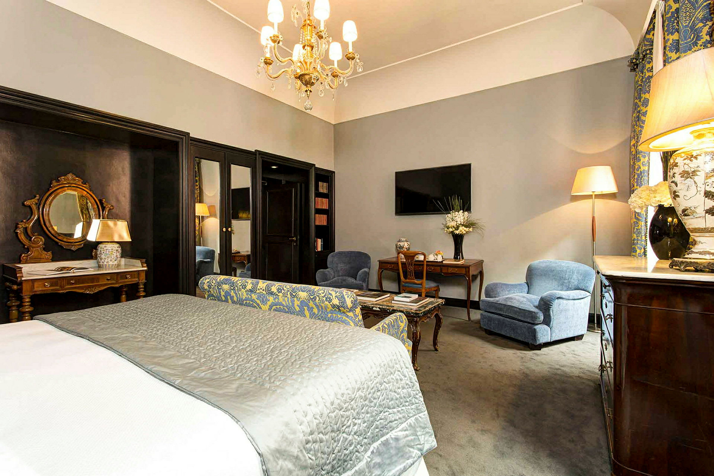 Et velinnredet hotellrom med en stor seng, sittemøbler og elegante interiørdetaljer. (AI-generert tekst)