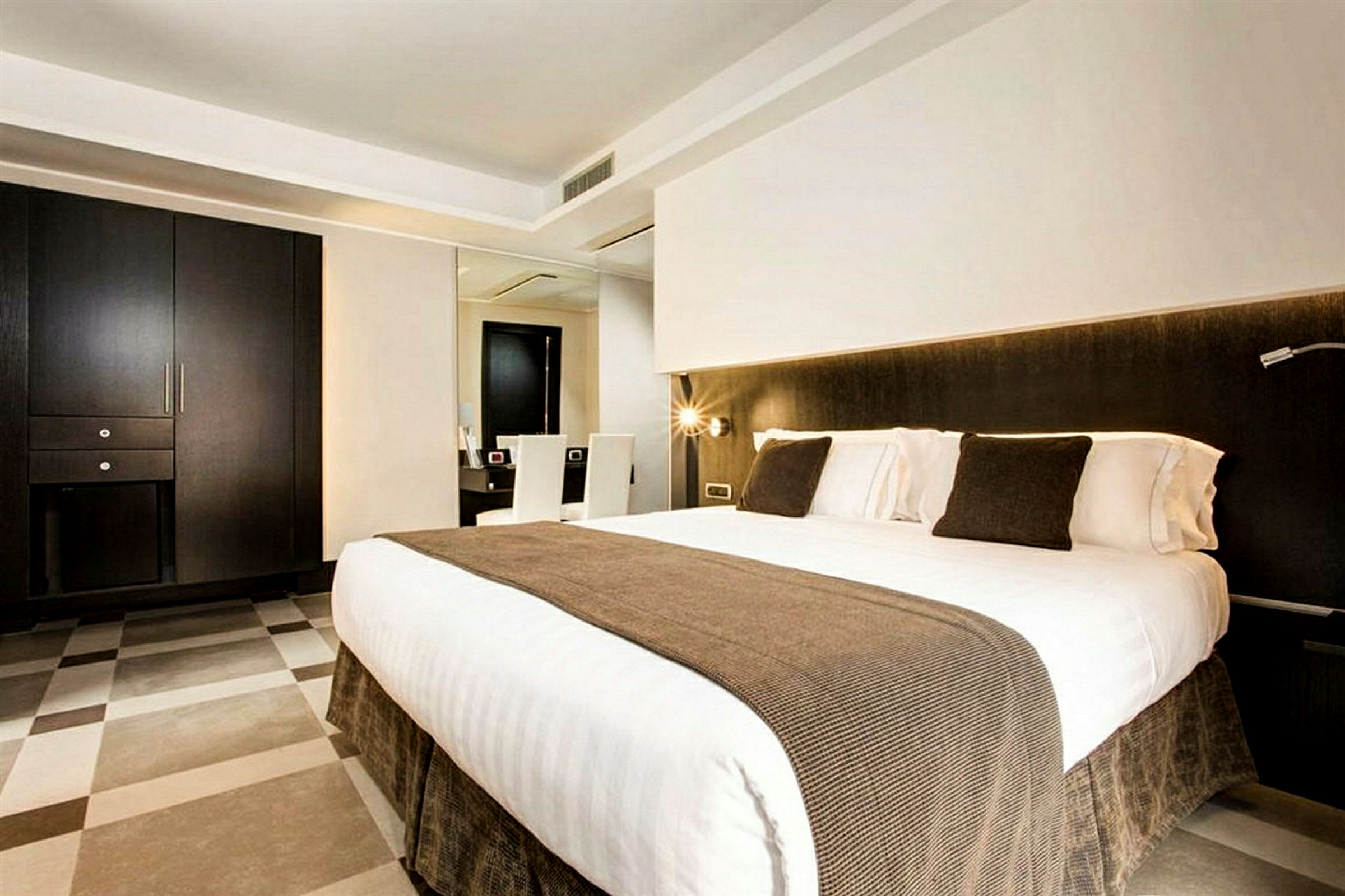Et moderne hotellrom med en dobbeltseng, brune detaljer og minimalistisk innredning. (AI-generert tekst)