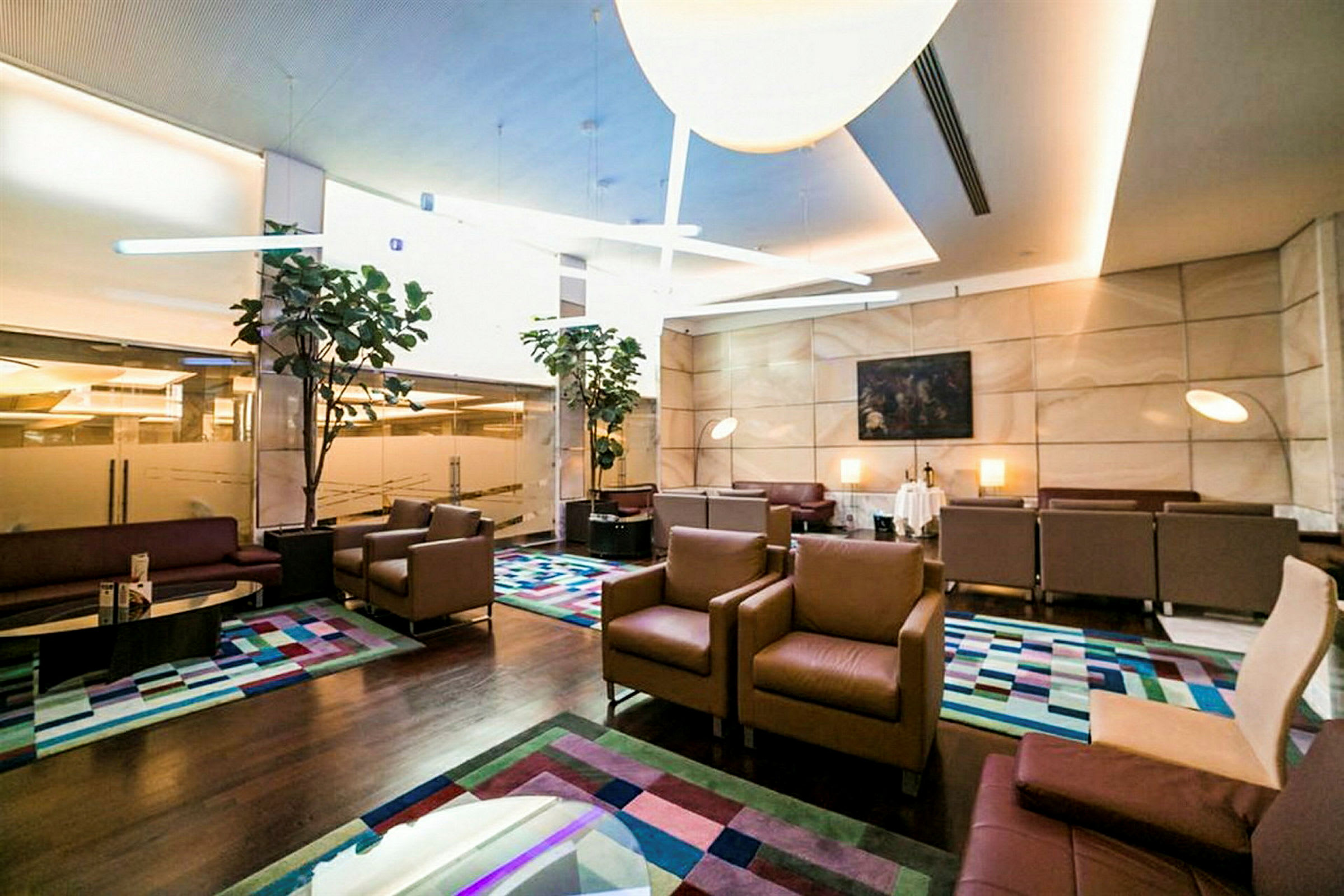 En romslig lounge med sittegrupper, fargerike tepper og planter. (AI-generert tekst)
