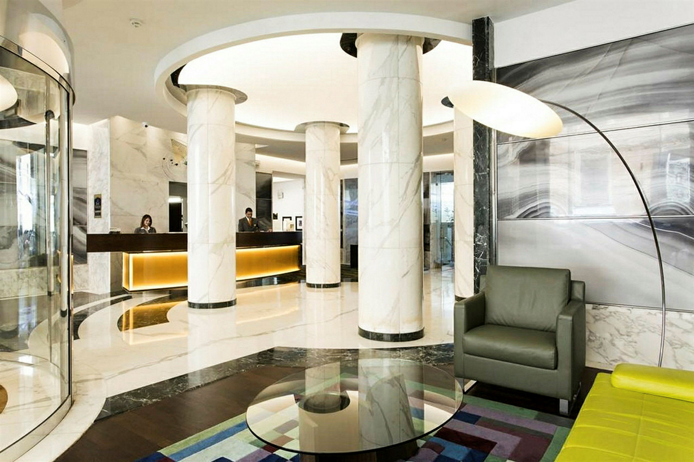 Moderne hotellobby med marmorsøyler, resepsjonsdisk og sittegruppe. (AI-generert tekst)