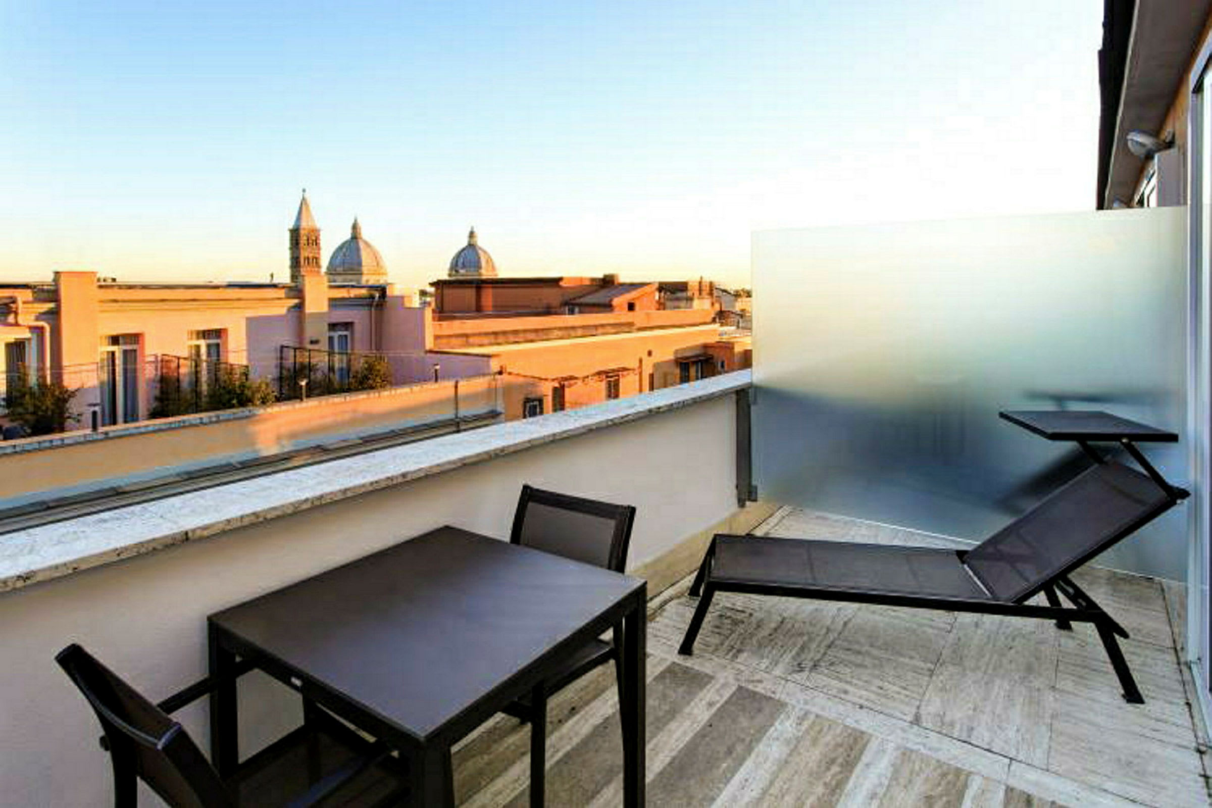 Terrasse med utsikt over bygninger og kirke kupler i bakgrunnen. (AI-generert tekst)