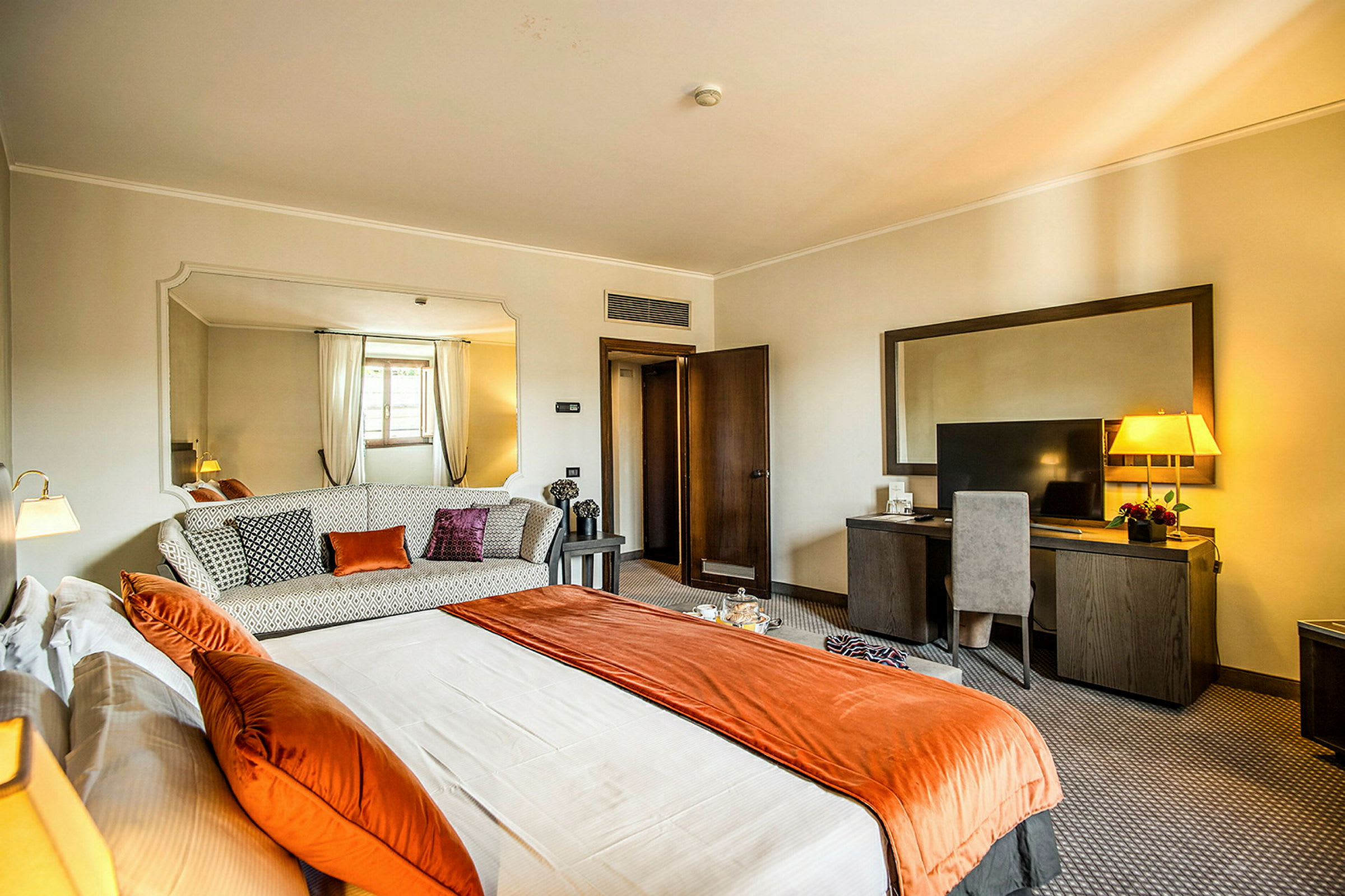Et hotellrom med en seng, sofa og skrivebord. (AI-generert tekst)