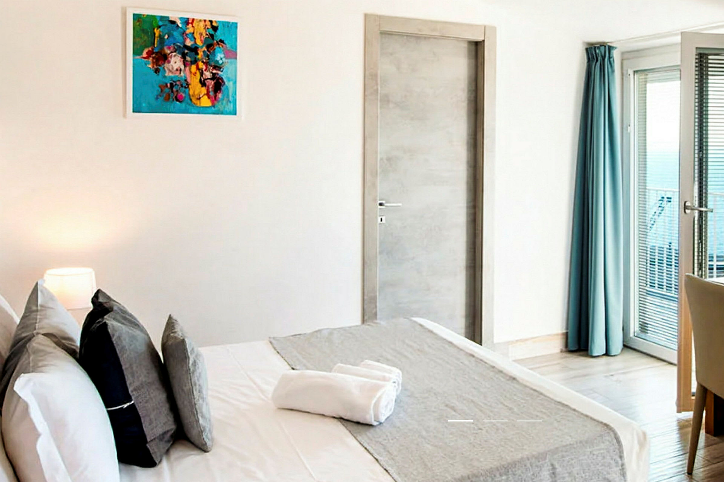 Moderne hotellrom med en dobbeltseng, kunst på veggen, garderobe og et vindu med blå gardiner. (AI-generert tekst)