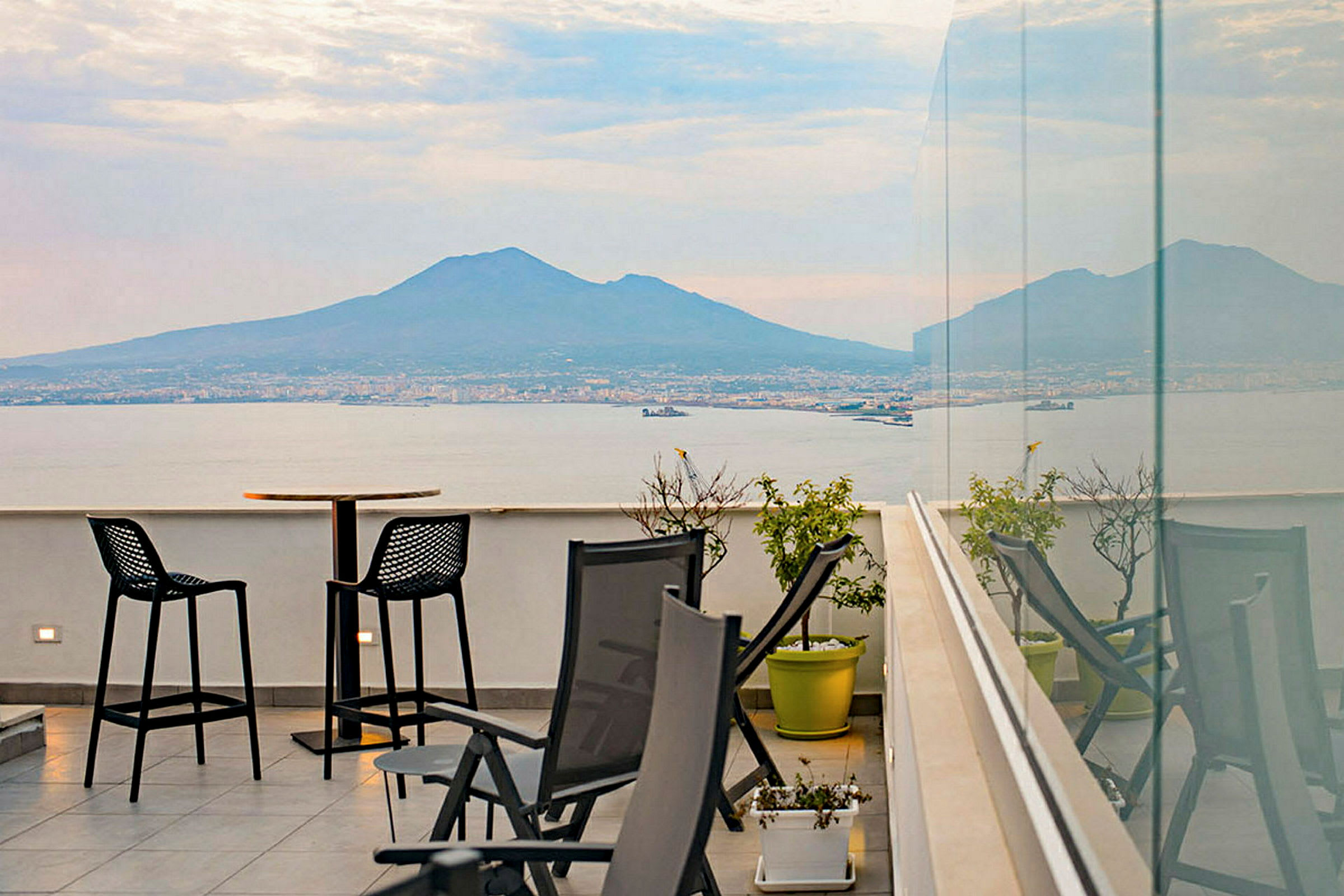 En terrasse med utsikt over havet og et fjell i bakgrunnen. (AI-generert tekst)