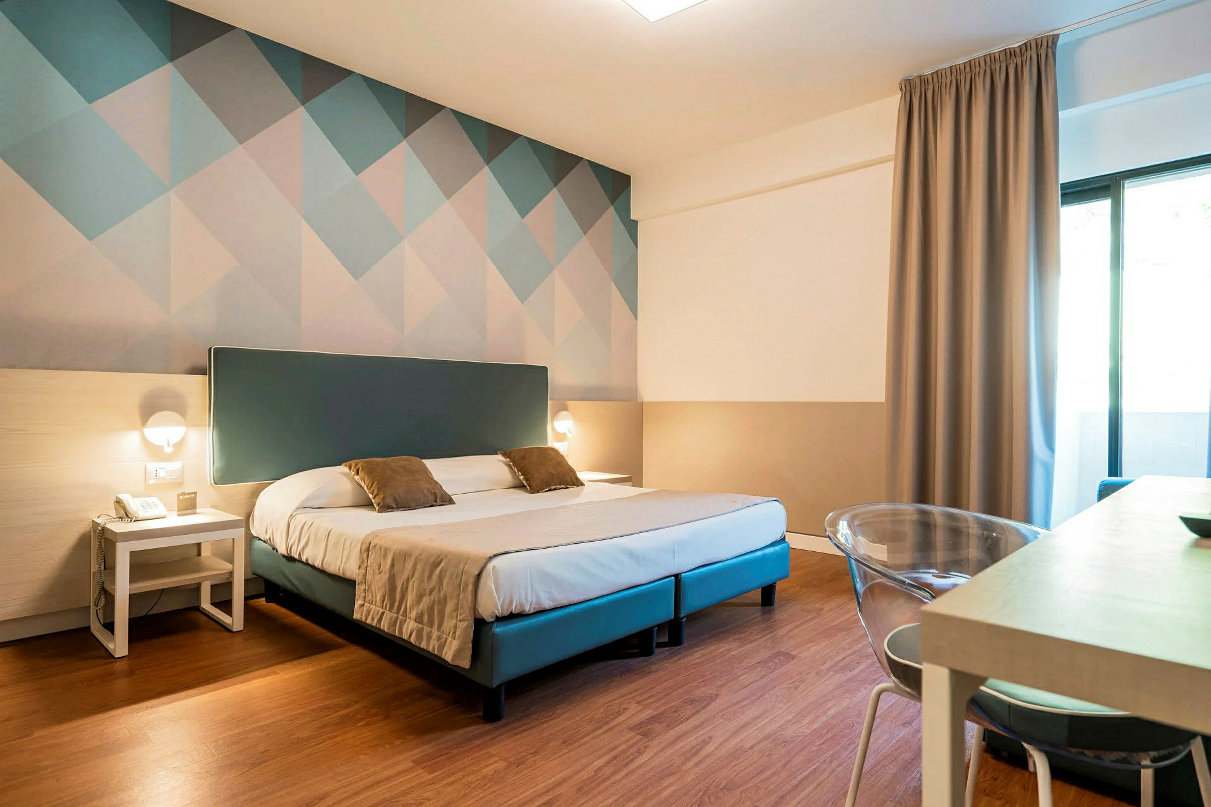Et hotellrom med en dobbeltseng, to nattbord og en dekorativ vegg bak sengen. (AI-generert tekst)