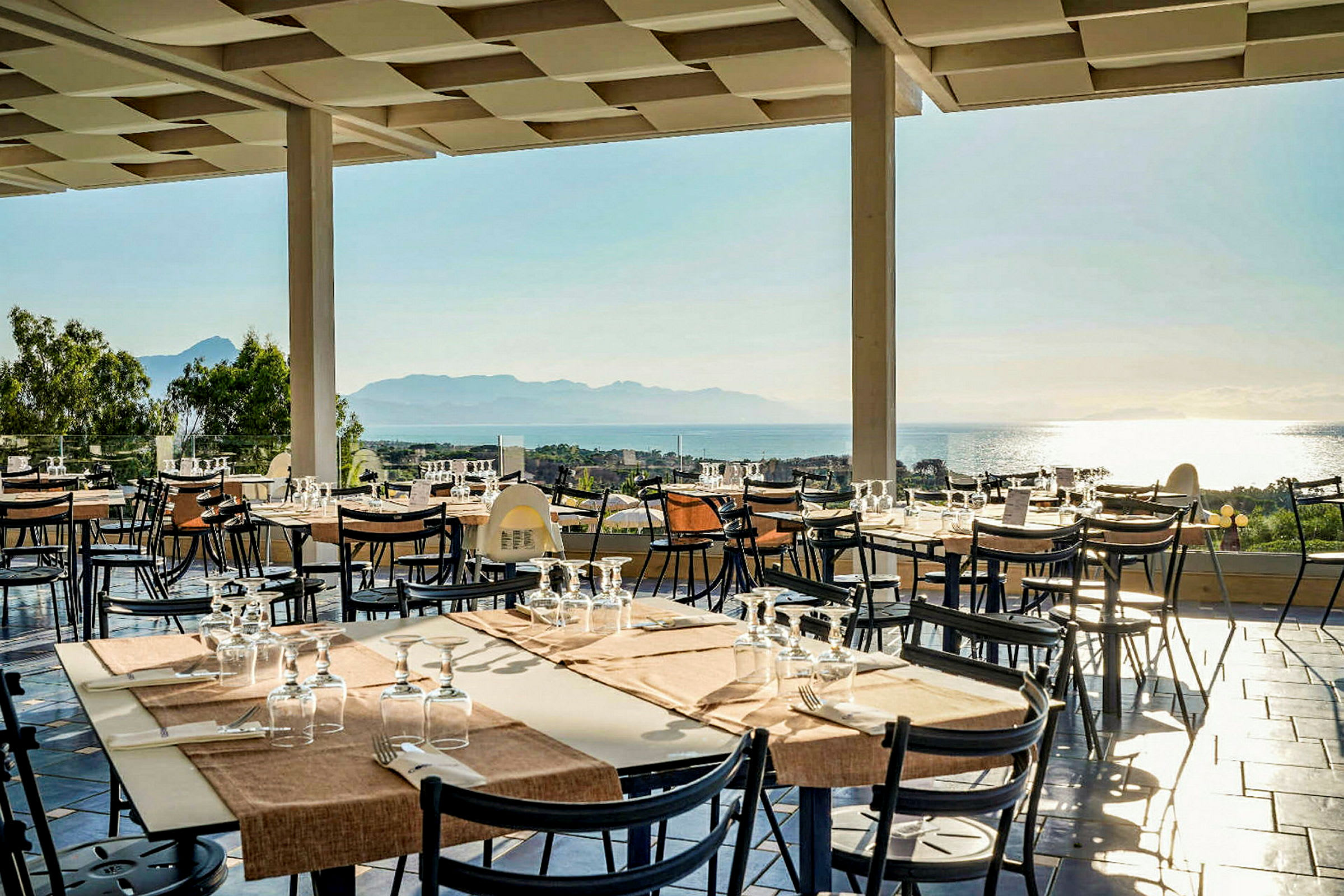 Terrasse med dekkede bord og utsikt over havet. (AI-generert tekst)