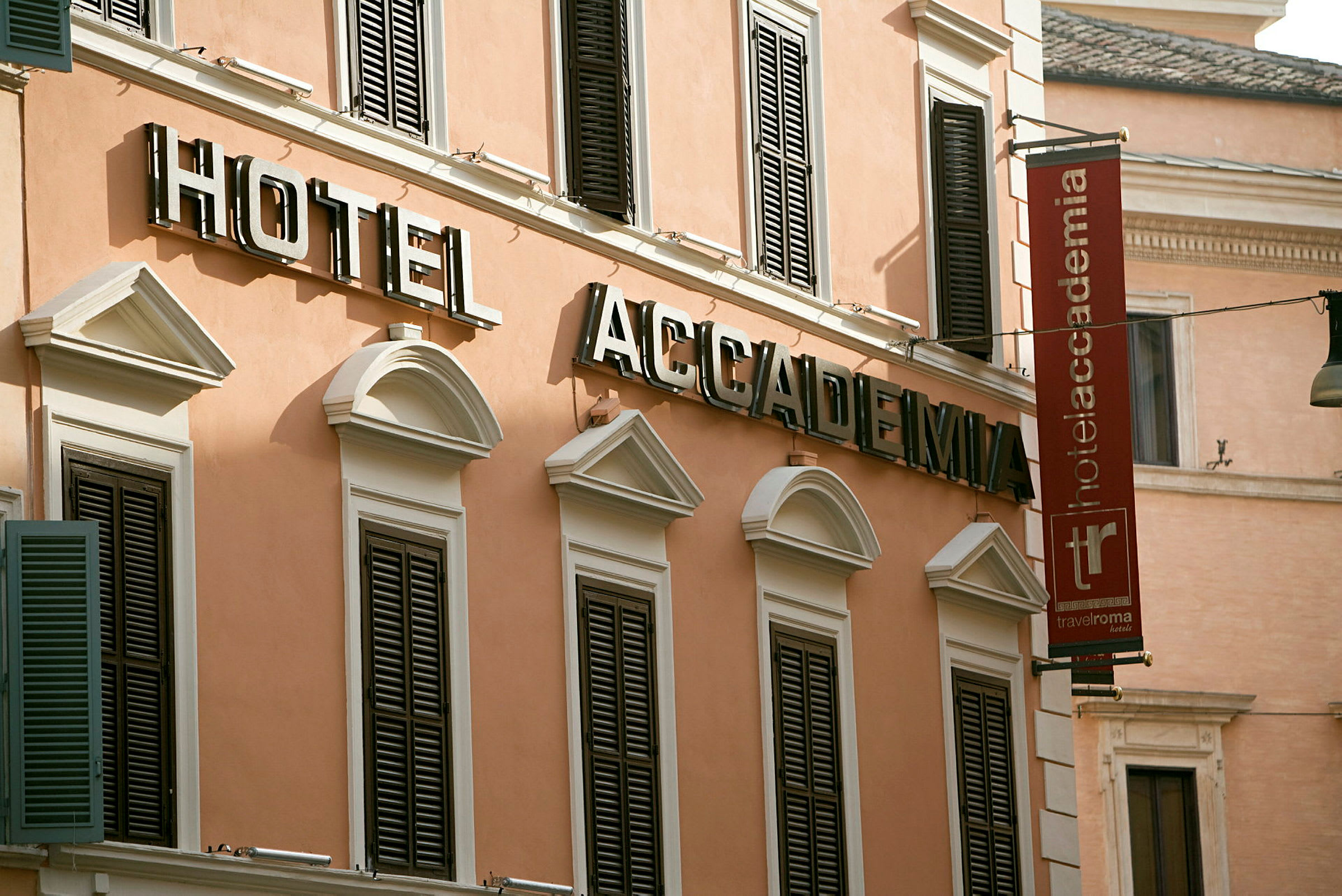 Fasade av hotellbygning med skilt som sier "Hotel Accademia" i store bokstaver. (AI-generert tekst)