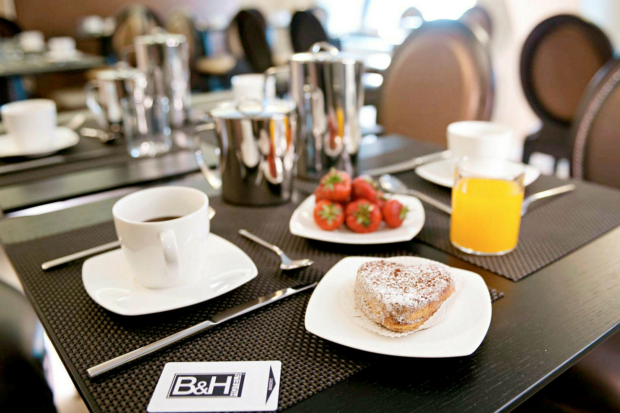 Frokostbord med kaffe, bakverk, friske jordbær og et glass appelsinjuice. (AI-generert tekst)